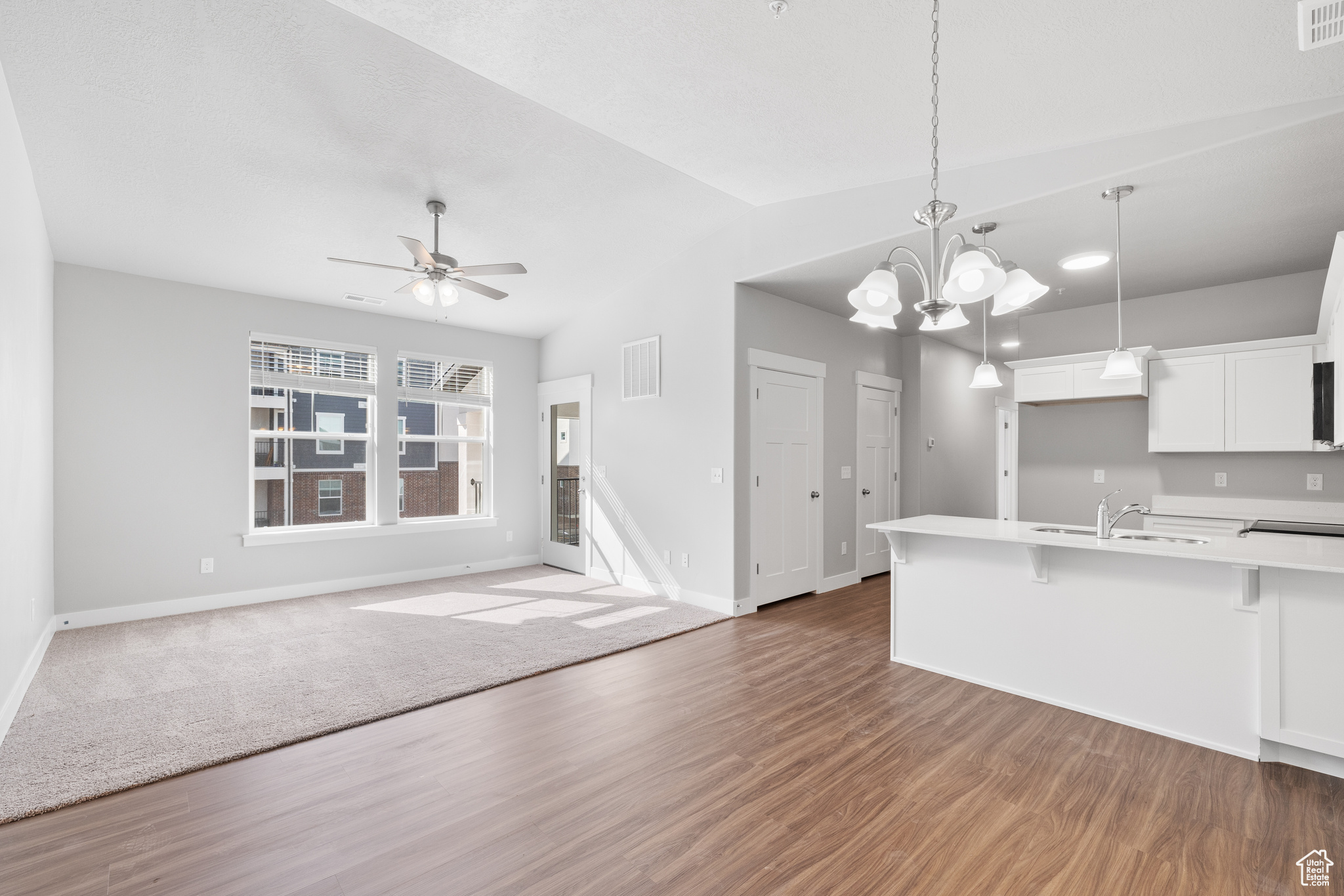 Kitchen featuring decorative light fixtures, a kitchen bar, white cabinetry, and dark hardwood / wood-style floors