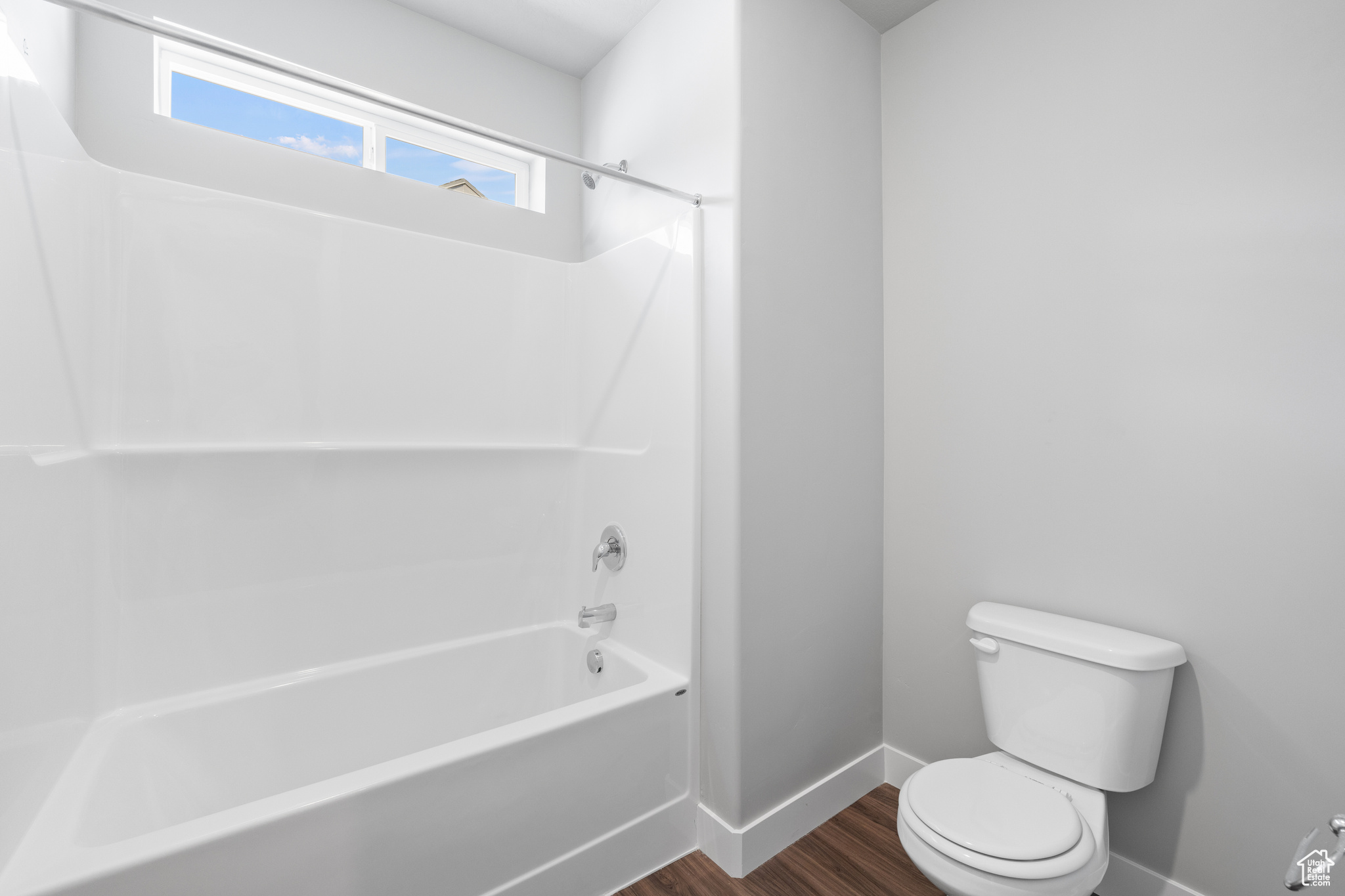 Bathroom with wood-type flooring, toilet, and shower / bathtub combination