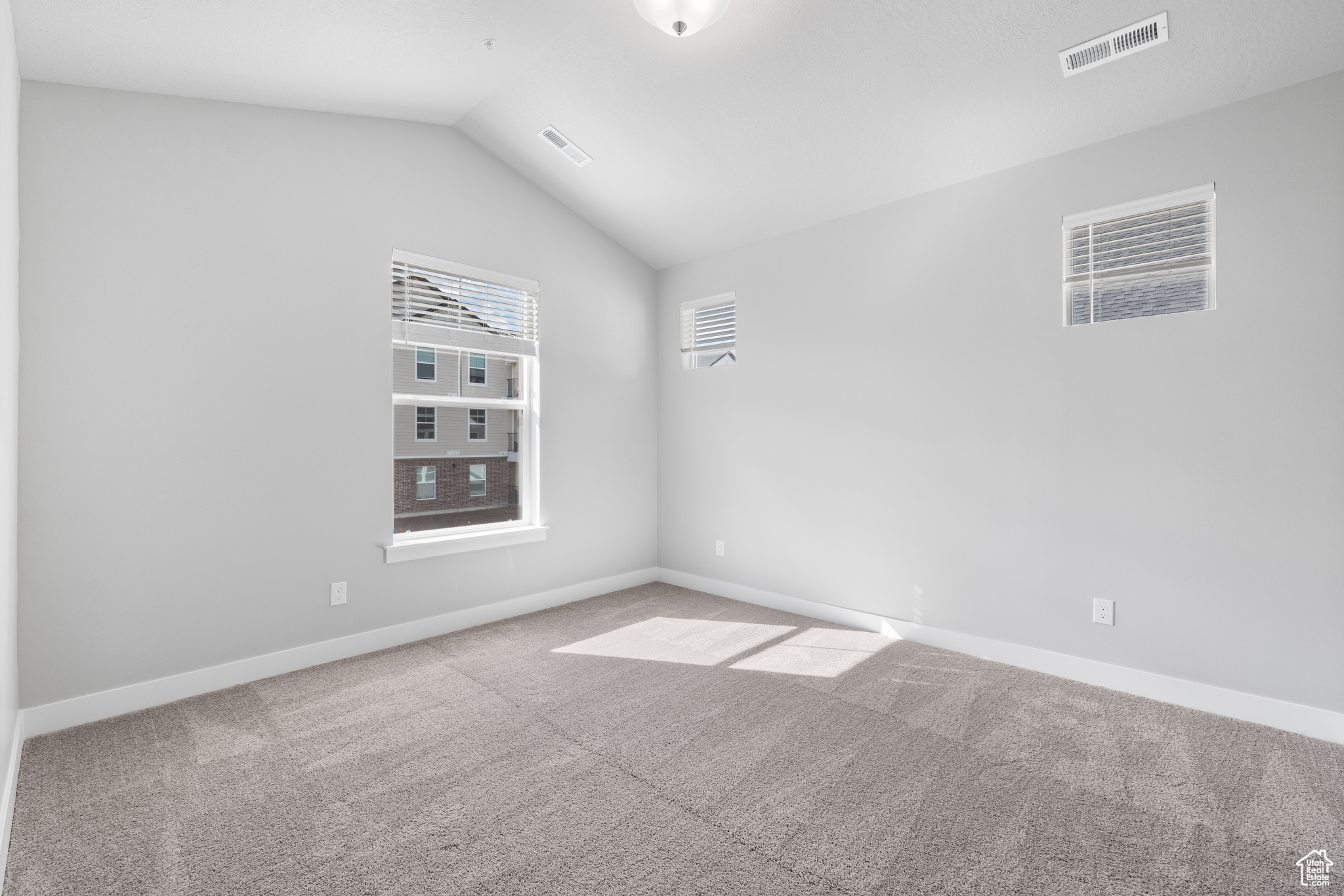 Carpeted empty room with lofted ceiling