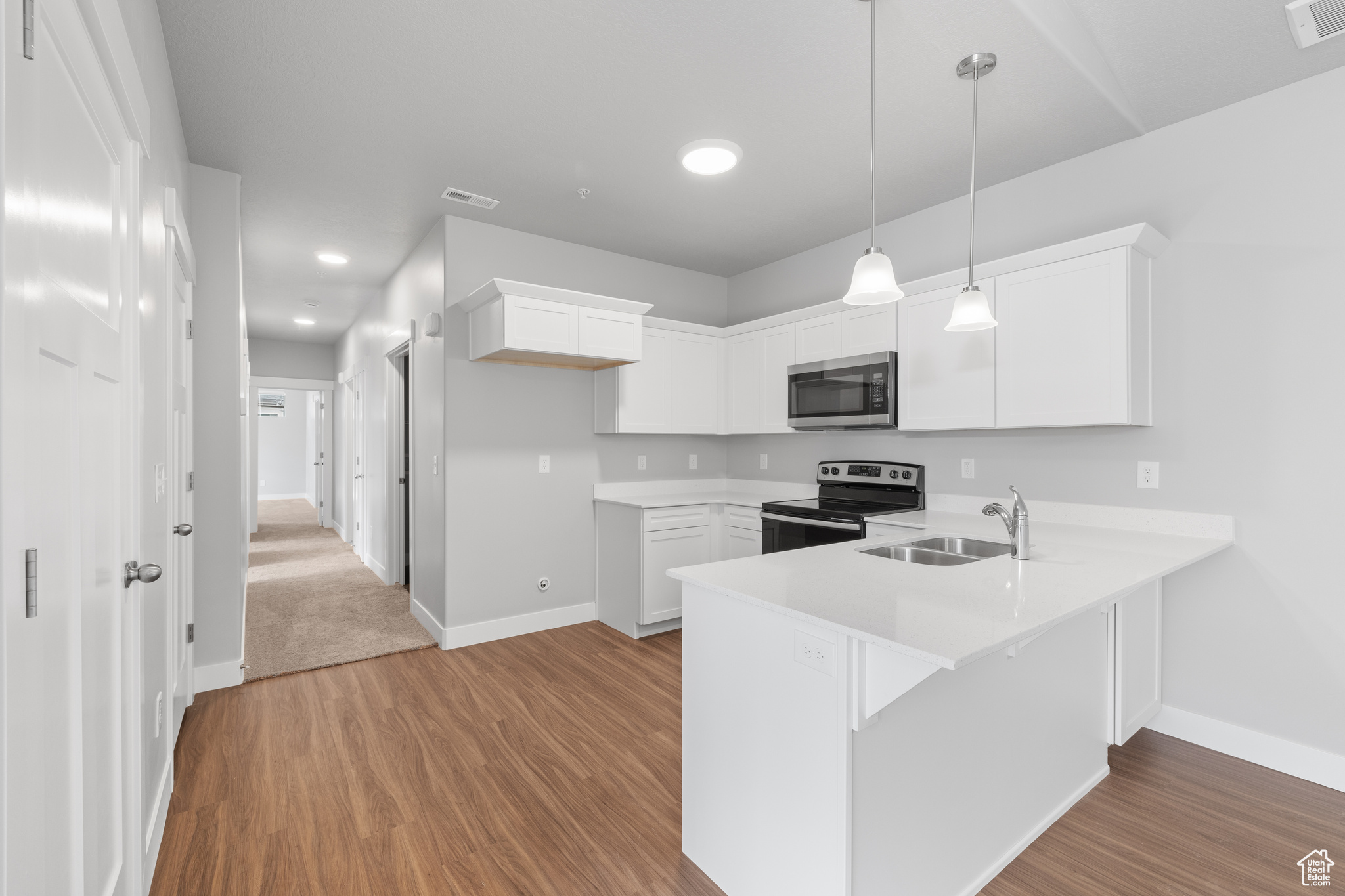 Kitchen with white cabinetry, carpet, appliances with stainless steel finishes, and sink