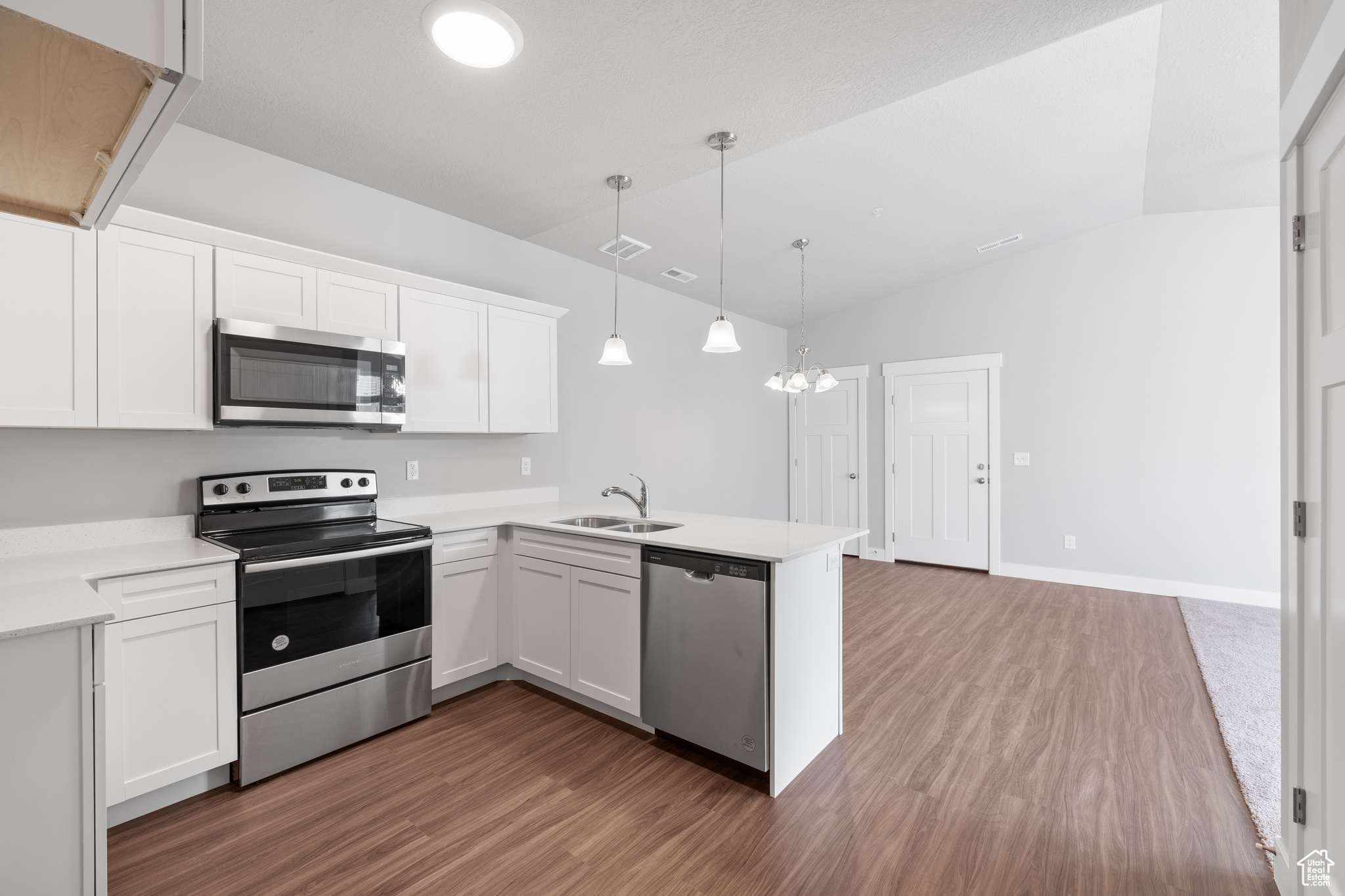 Kitchen with appliances with stainless steel finishes, white cabinetry, sink, and kitchen peninsula