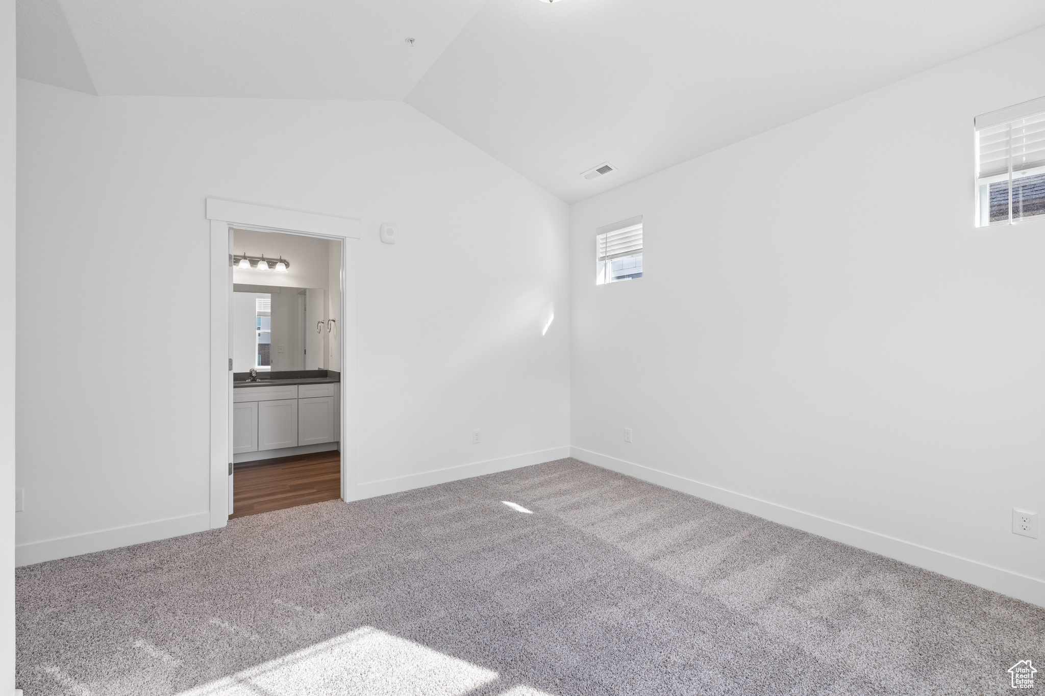 Carpeted empty room with a healthy amount of sunlight, sink, and vaulted ceiling