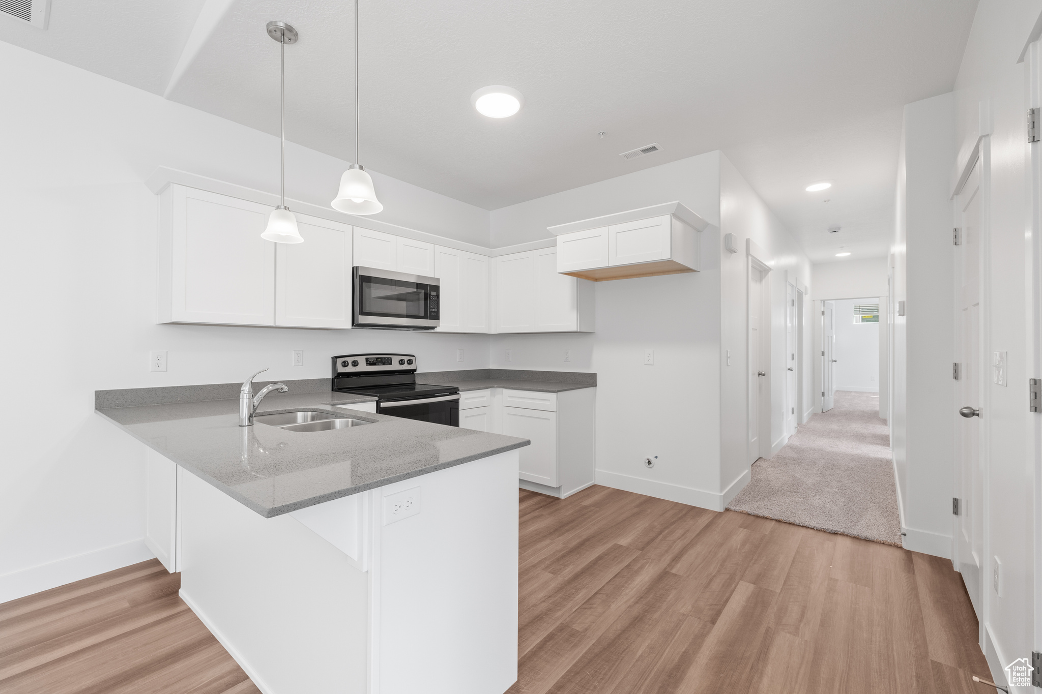 Kitchen featuring appliances with stainless steel finishes, kitchen peninsula, and light hardwood / wood-style flooring