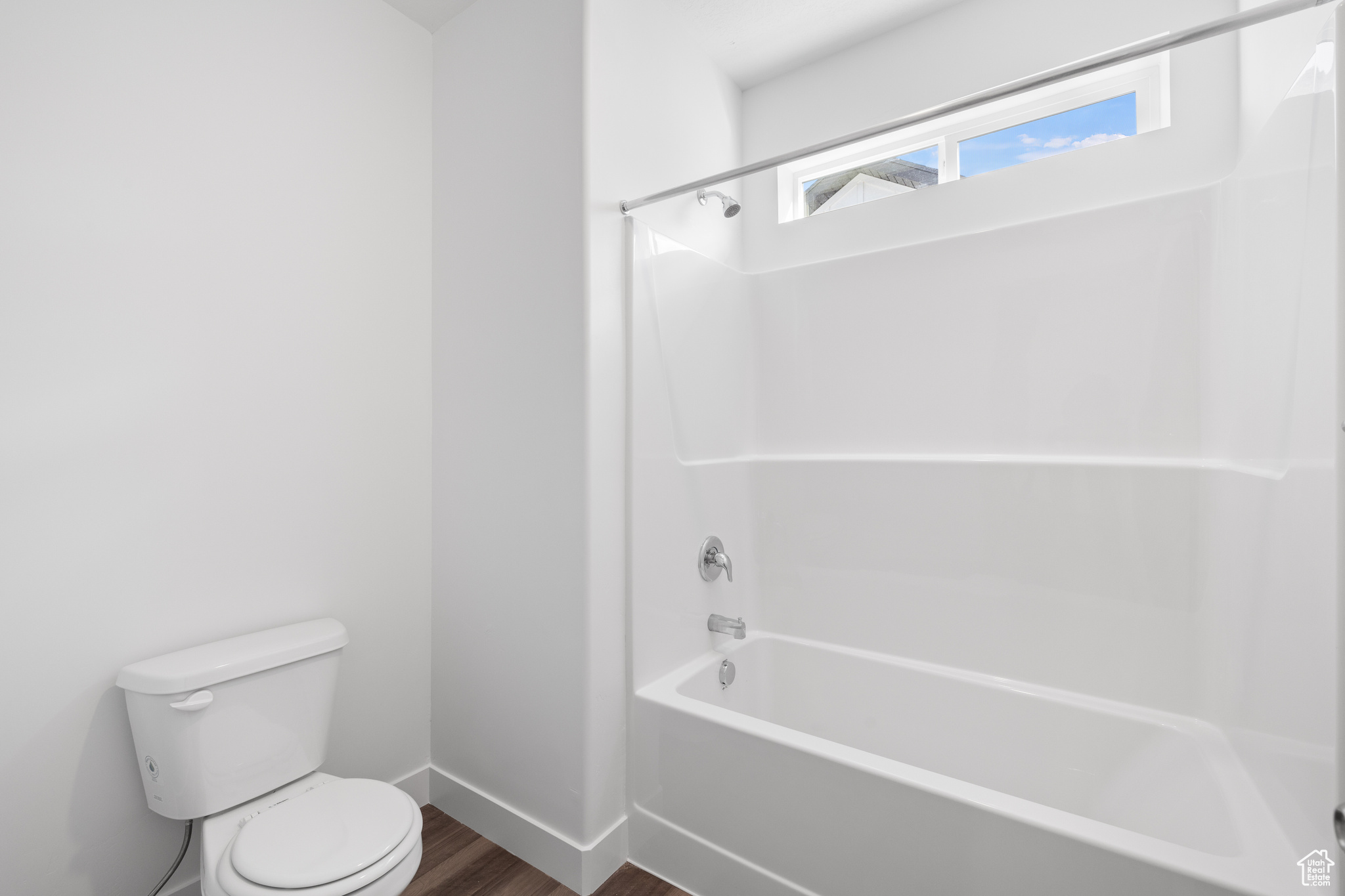 Bathroom with tub / shower combination, toilet, and wood-type flooring