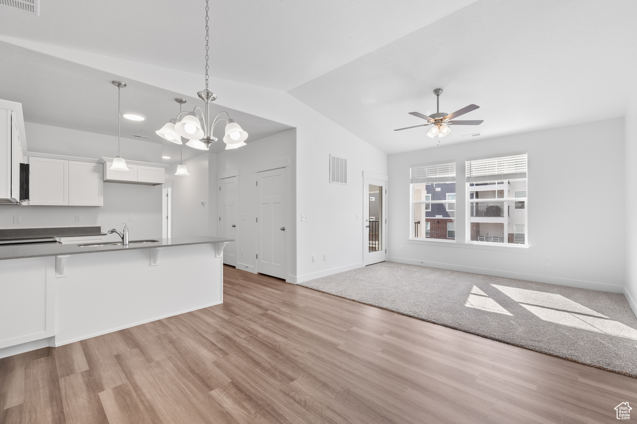 Kitchen with hanging light fixtures, white cabinetry, and light hardwood / wood-style floors