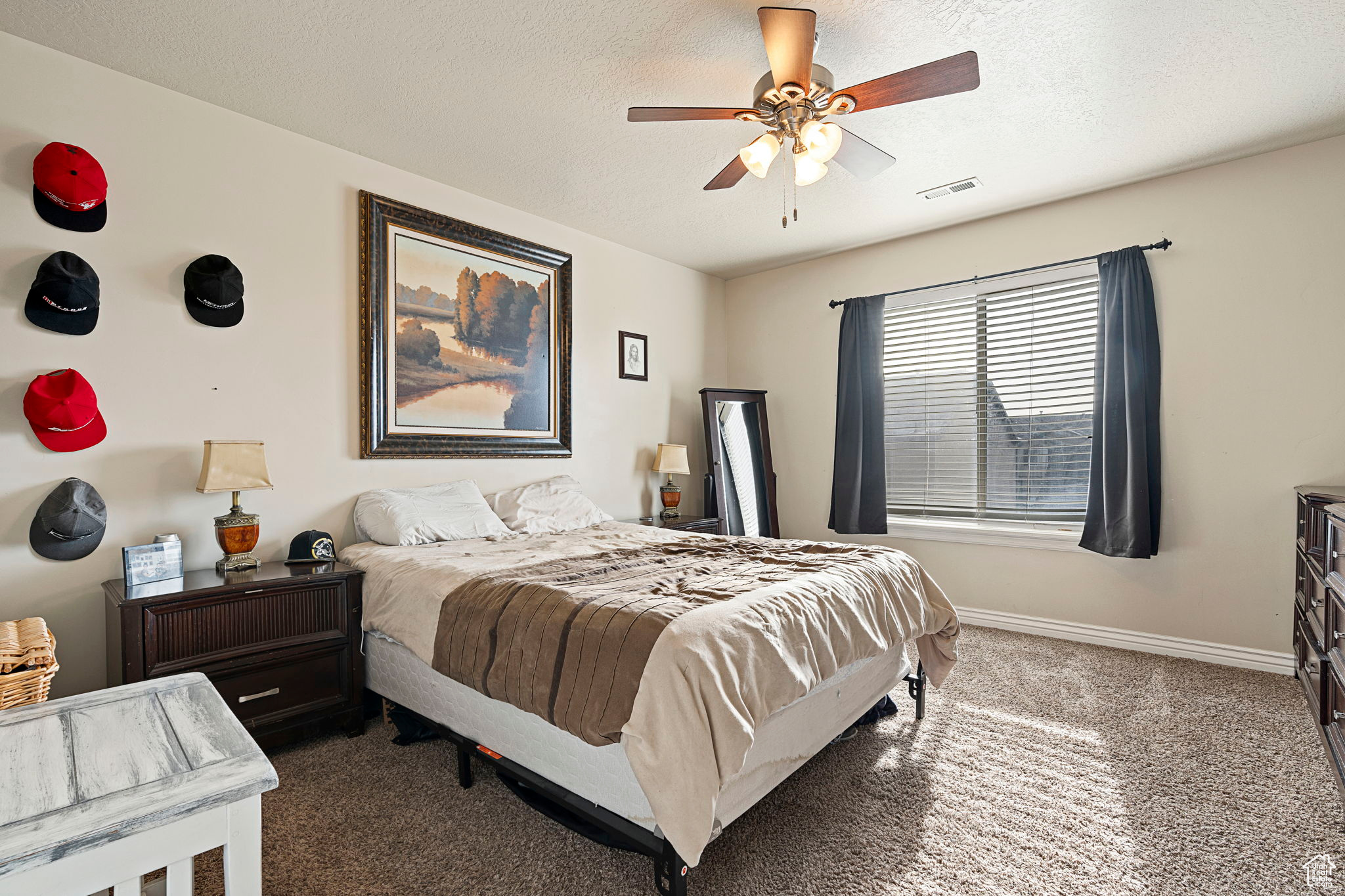 Bedroom featuring a textured ceiling, dark colored carpet, and ceiling fan