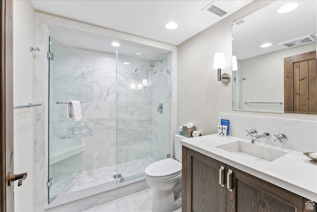 Bathroom featuring tile floors, walk in shower, toilet, and large vanity