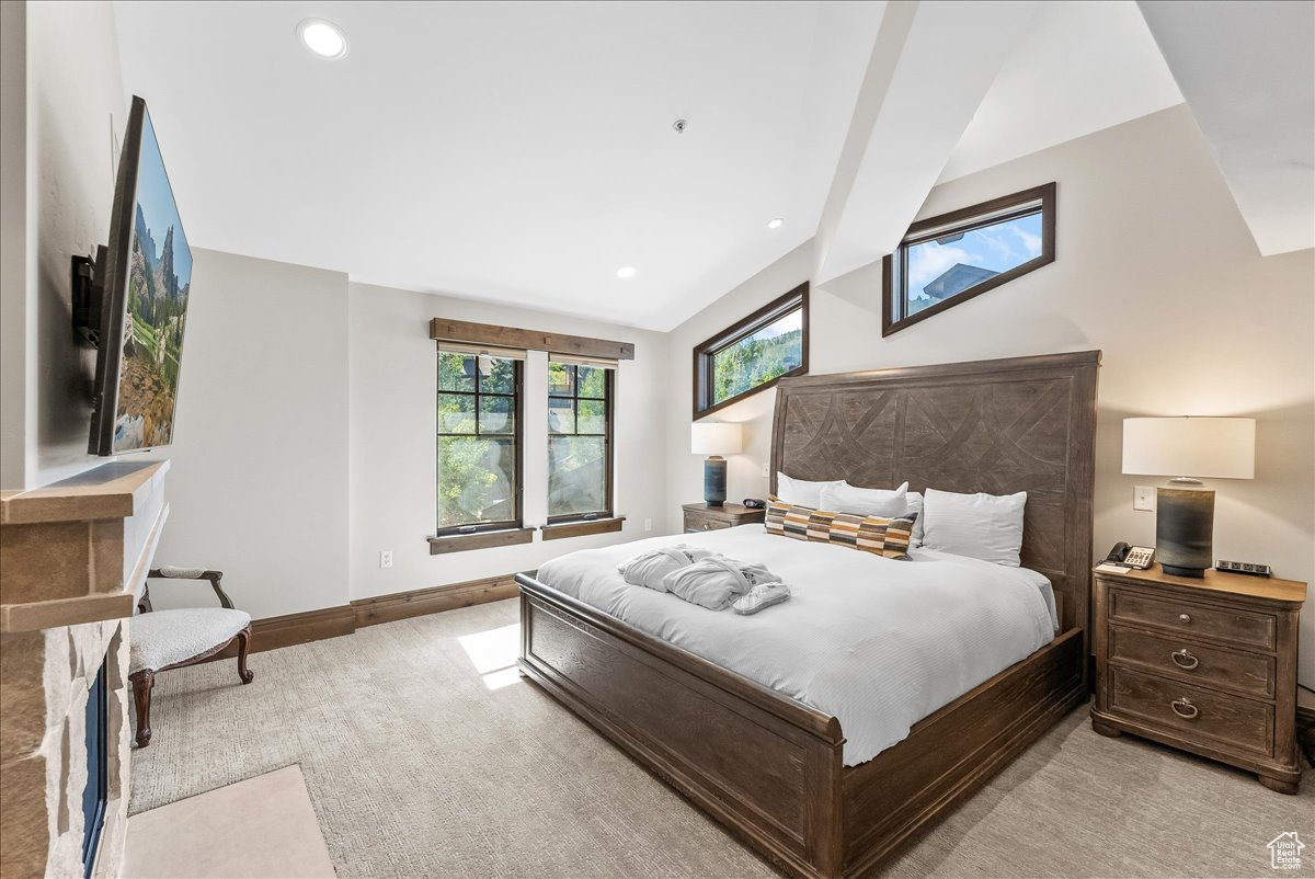 Carpeted bedroom with lofted ceiling with beams