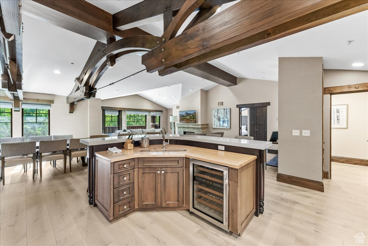 Kitchen with lofted ceiling with beams, light hardwood / wood-style floors, and beverage cooler