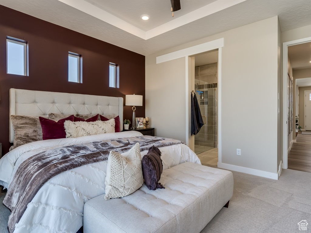 Bedroom with connected bathroom, light carpet, and ceiling fan