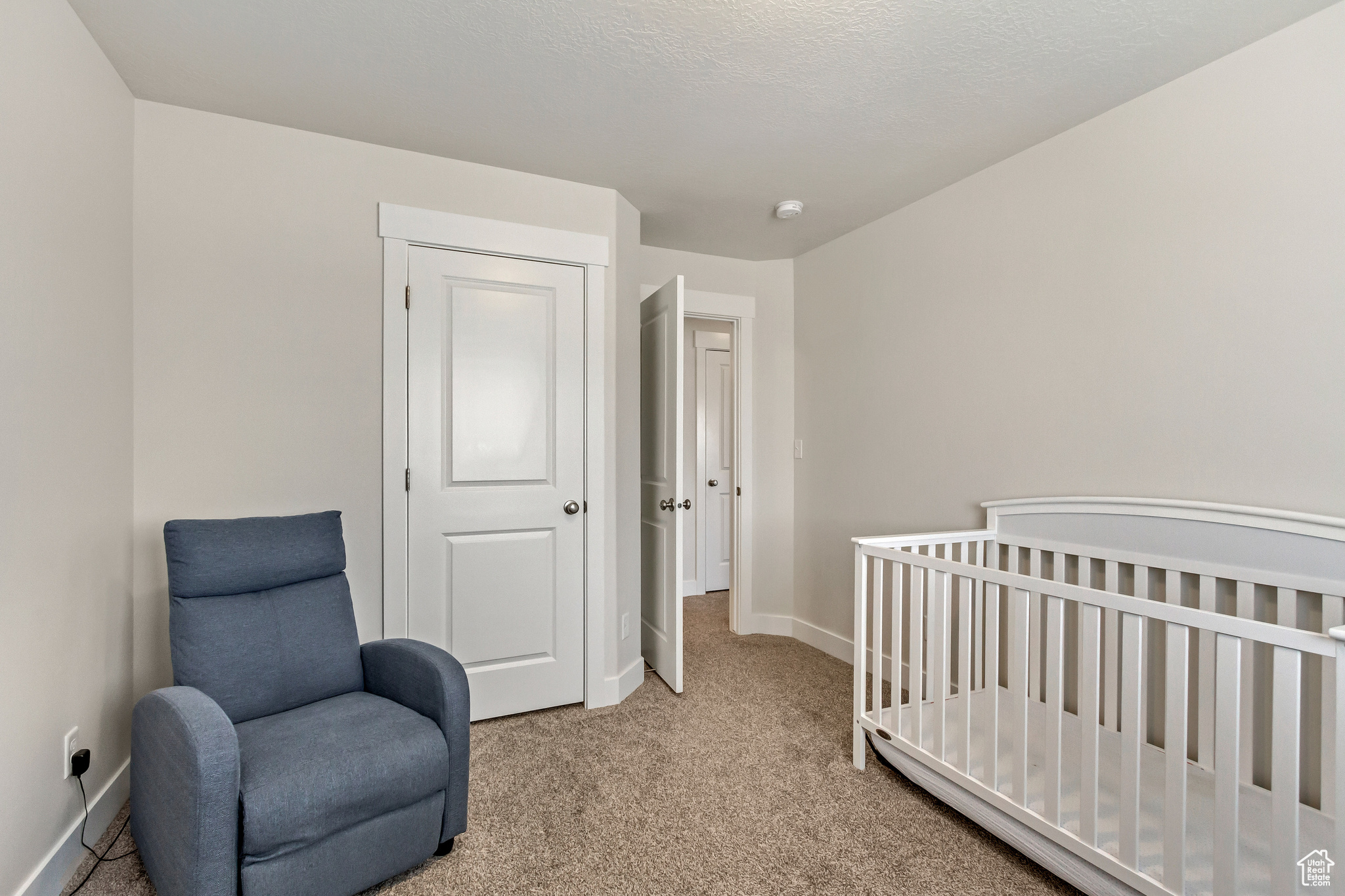 Bedroom with a crib, a closet, and light colored carpet