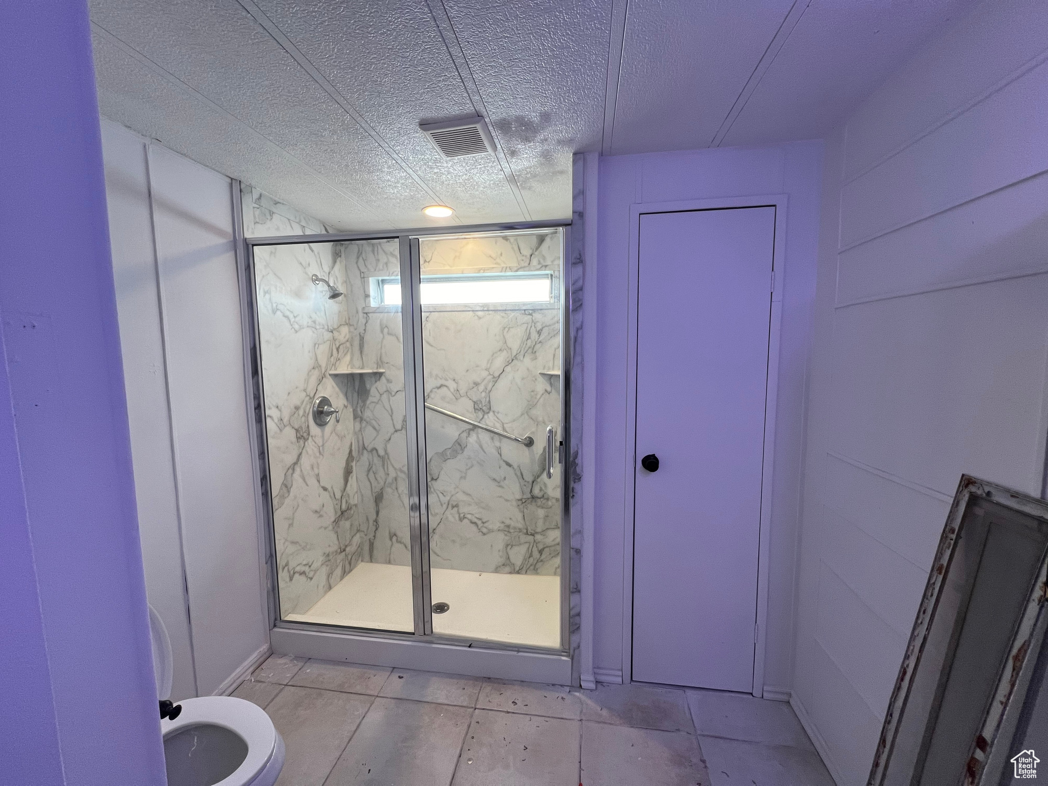 Bathroom with a shower with door, tile floors, a textured ceiling, and toilet