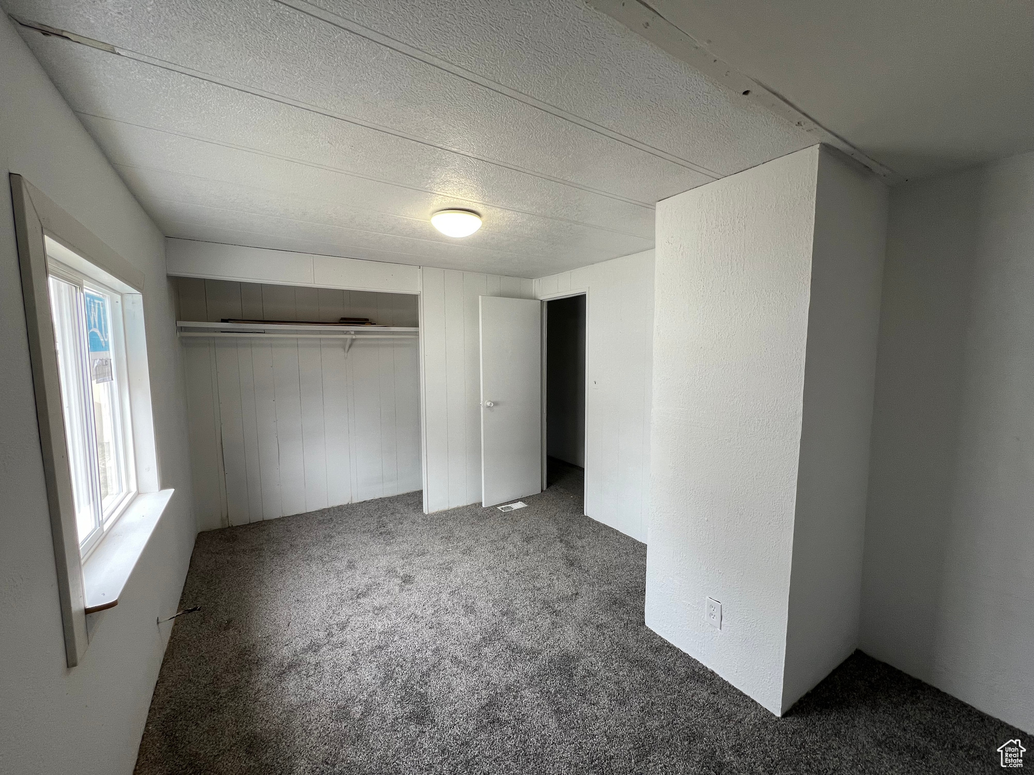 Unfurnished bedroom with a closet, carpet flooring, and a textured ceiling