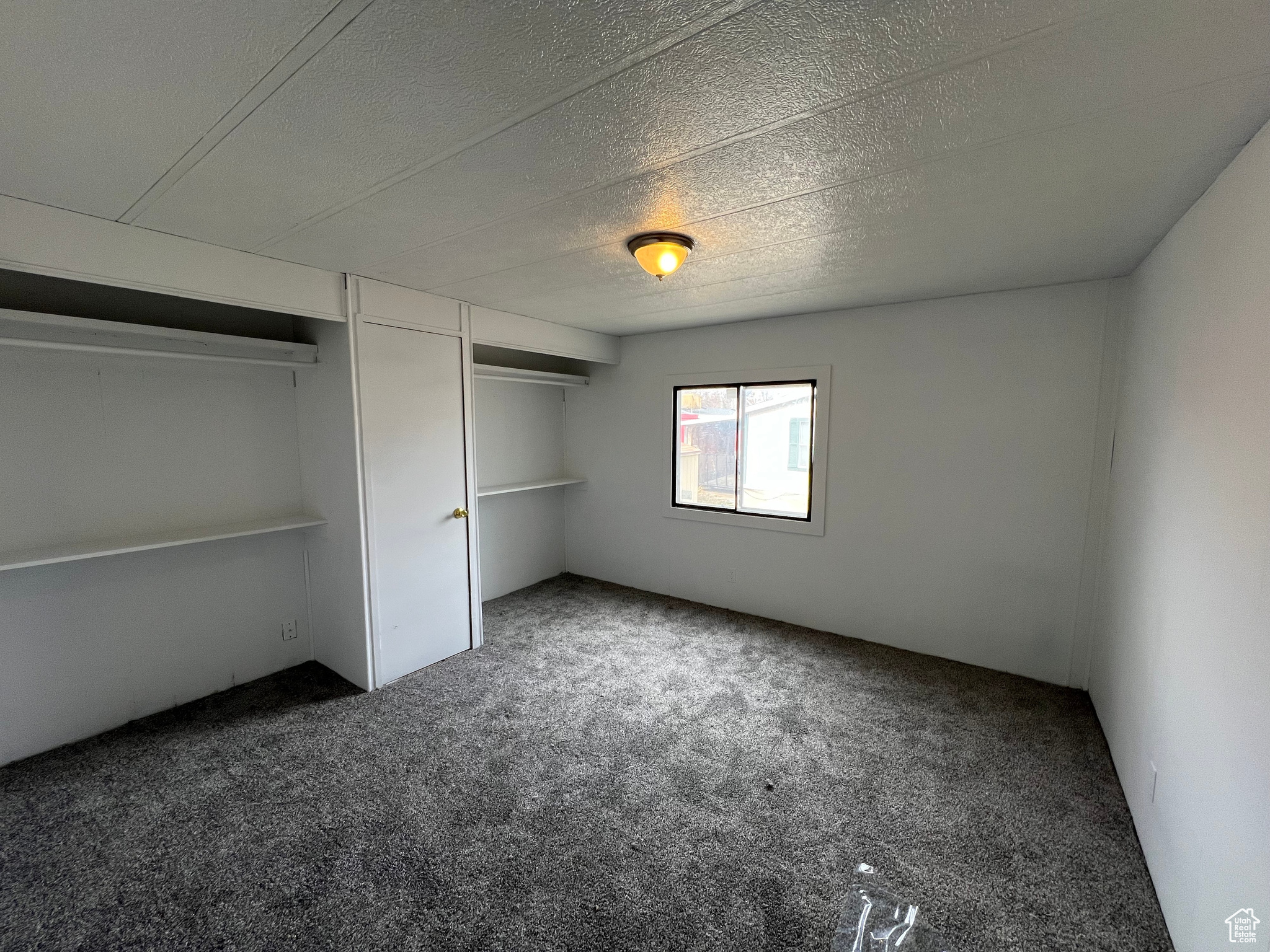 Unfurnished bedroom with dark carpet and a textured ceiling