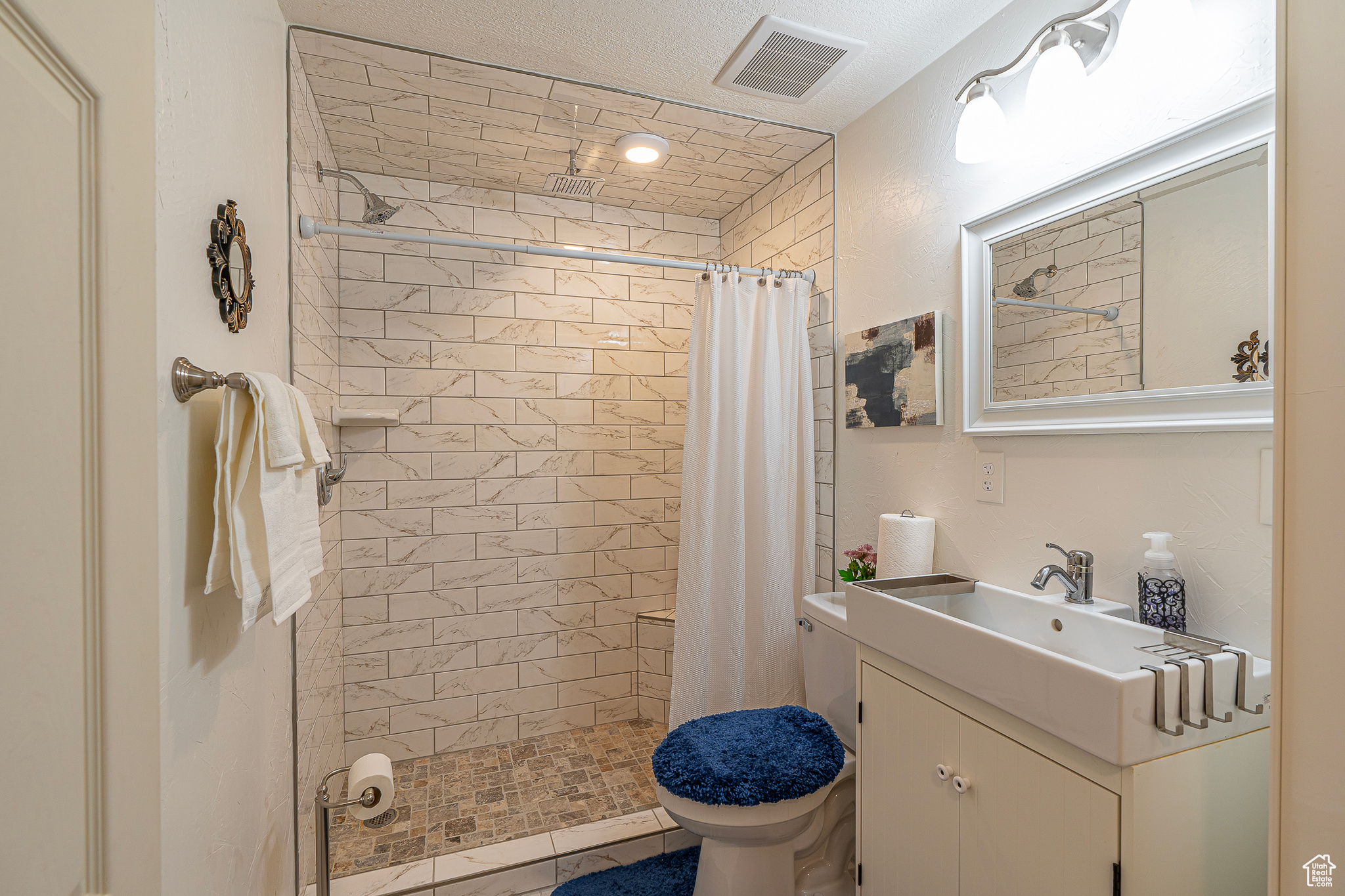 Bathroom featuring a shower with curtain, large vanity, and toilet