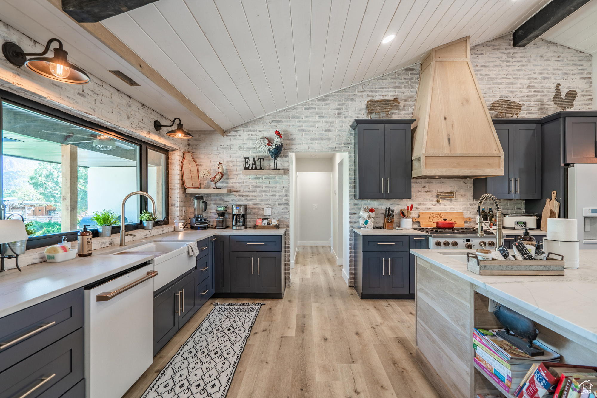 Kitchen featuring white appliances, light hardwood / wood-style flooring, custom range hood, backsplash, and vaulted ceiling with beams