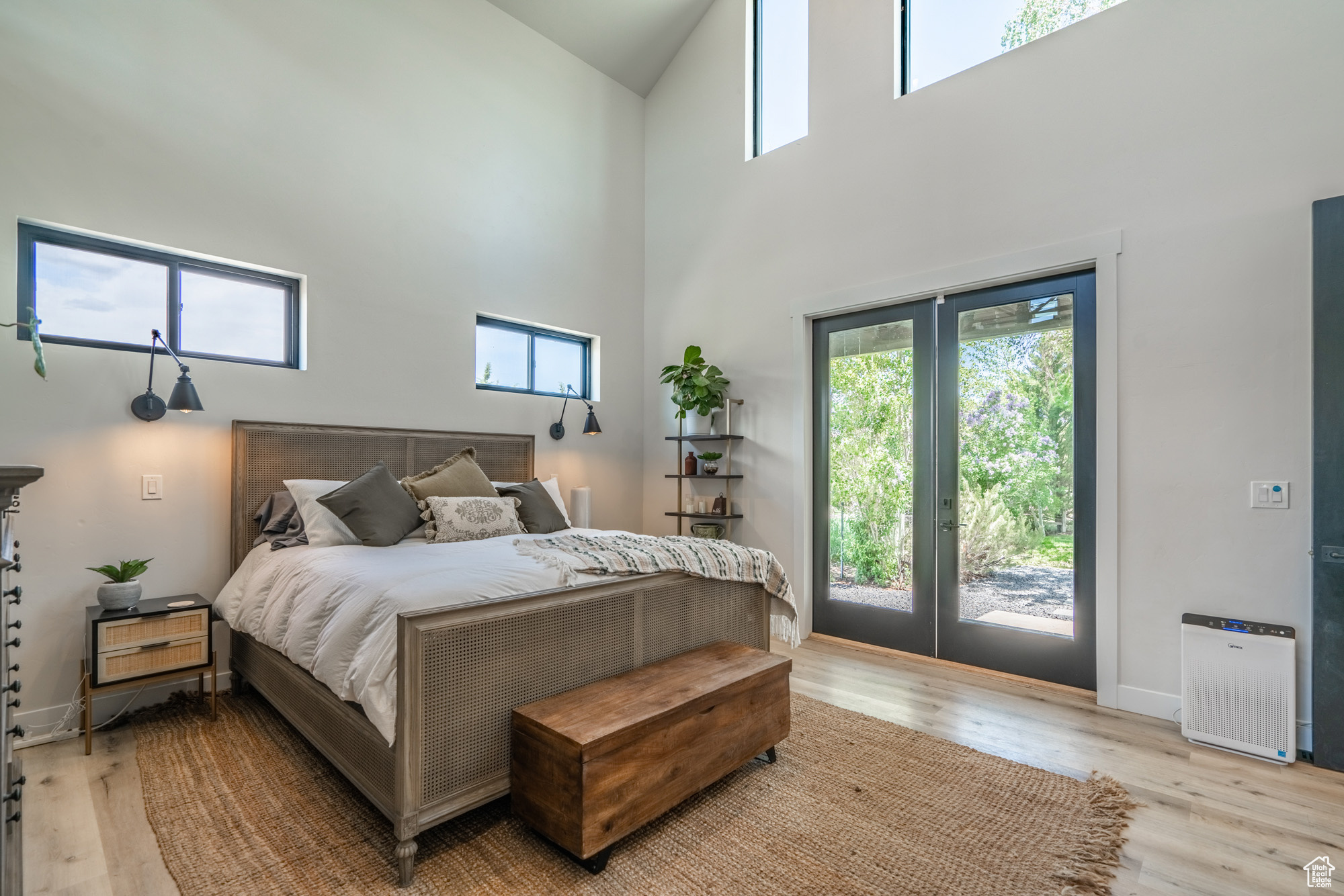 Bedroom with french doors, light hardwood / wood-style floors, a towering ceiling, and access to exterior