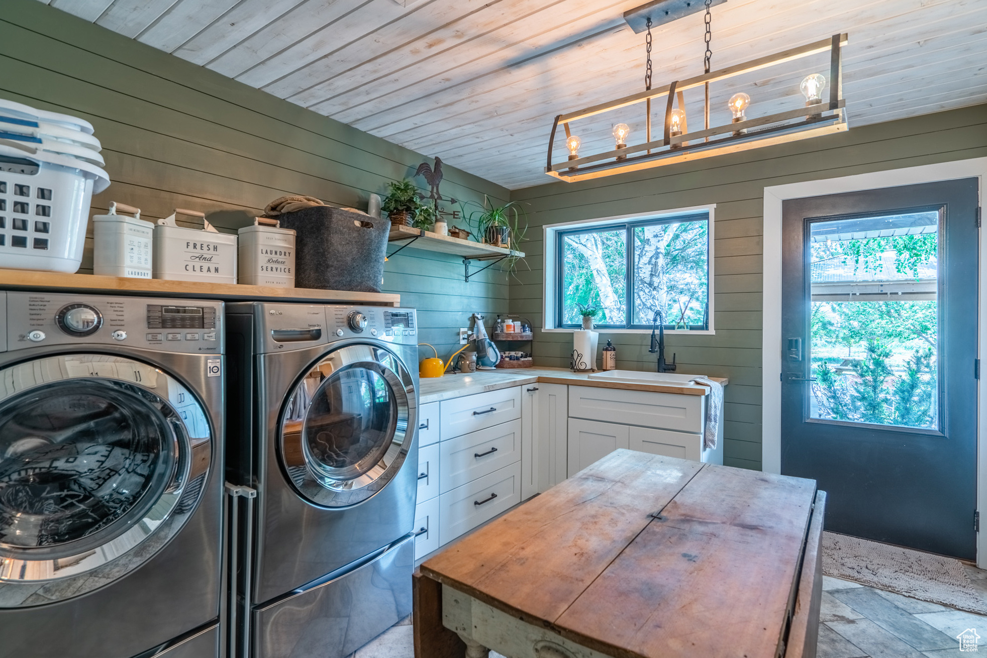 Laundry area with washer and dryer, wooden walls, wood ceiling, a notable chandelier, and sink