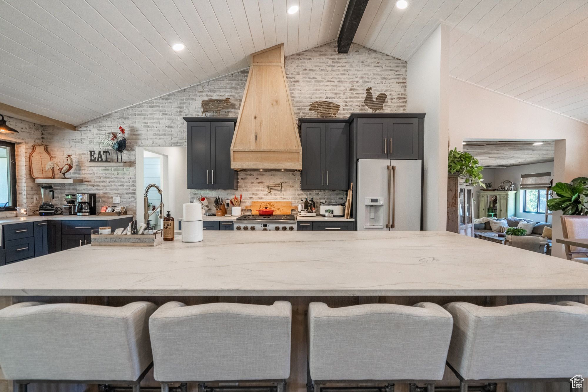 Interior space with a breakfast bar area, high end white fridge, custom range hood, backsplash, and a kitchen island