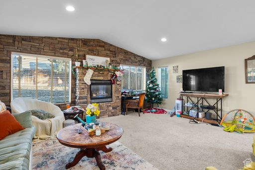 Living room featuring a fireplace, light carpet, and vaulted ceiling