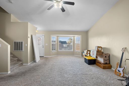 Sitting room featuring light colored carpet, ceiling fan, and vaulted ceiling