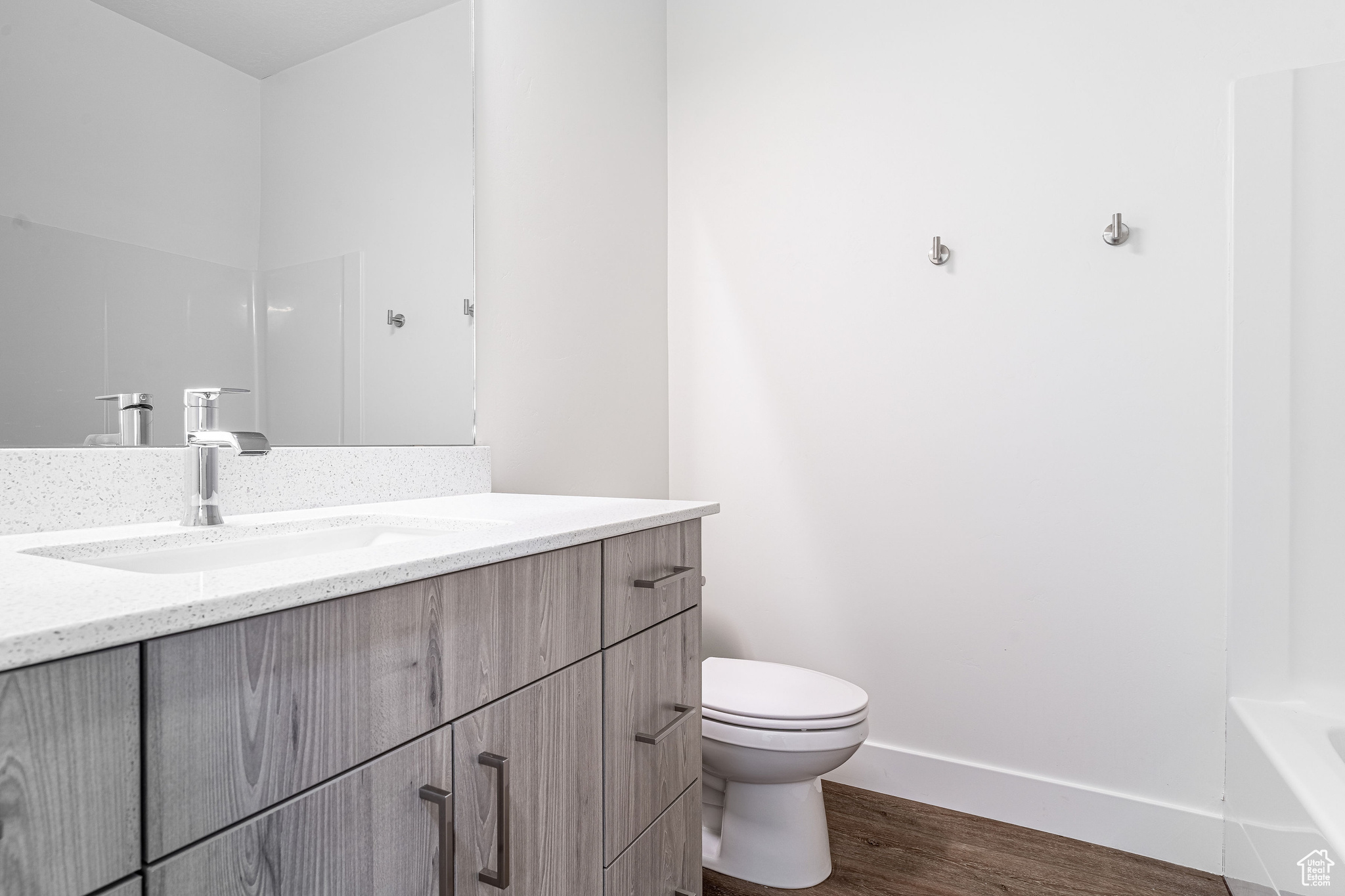 Full bathroom with oversized vanity, toilet,  shower combination, and hardwood / wood-style floors