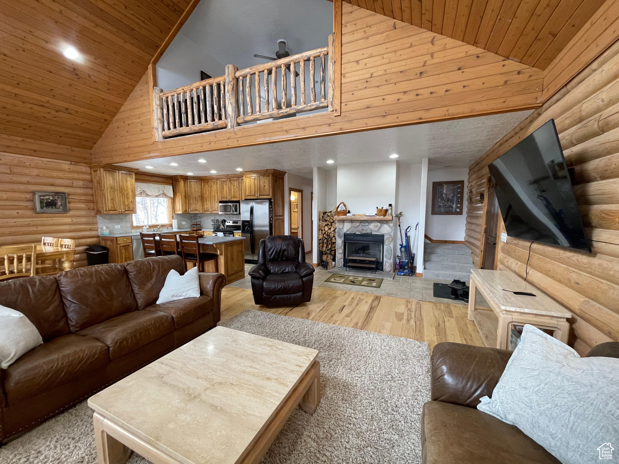 Living room featuring light hardwood / wood-style flooring, log walls, and high vaulted ceiling