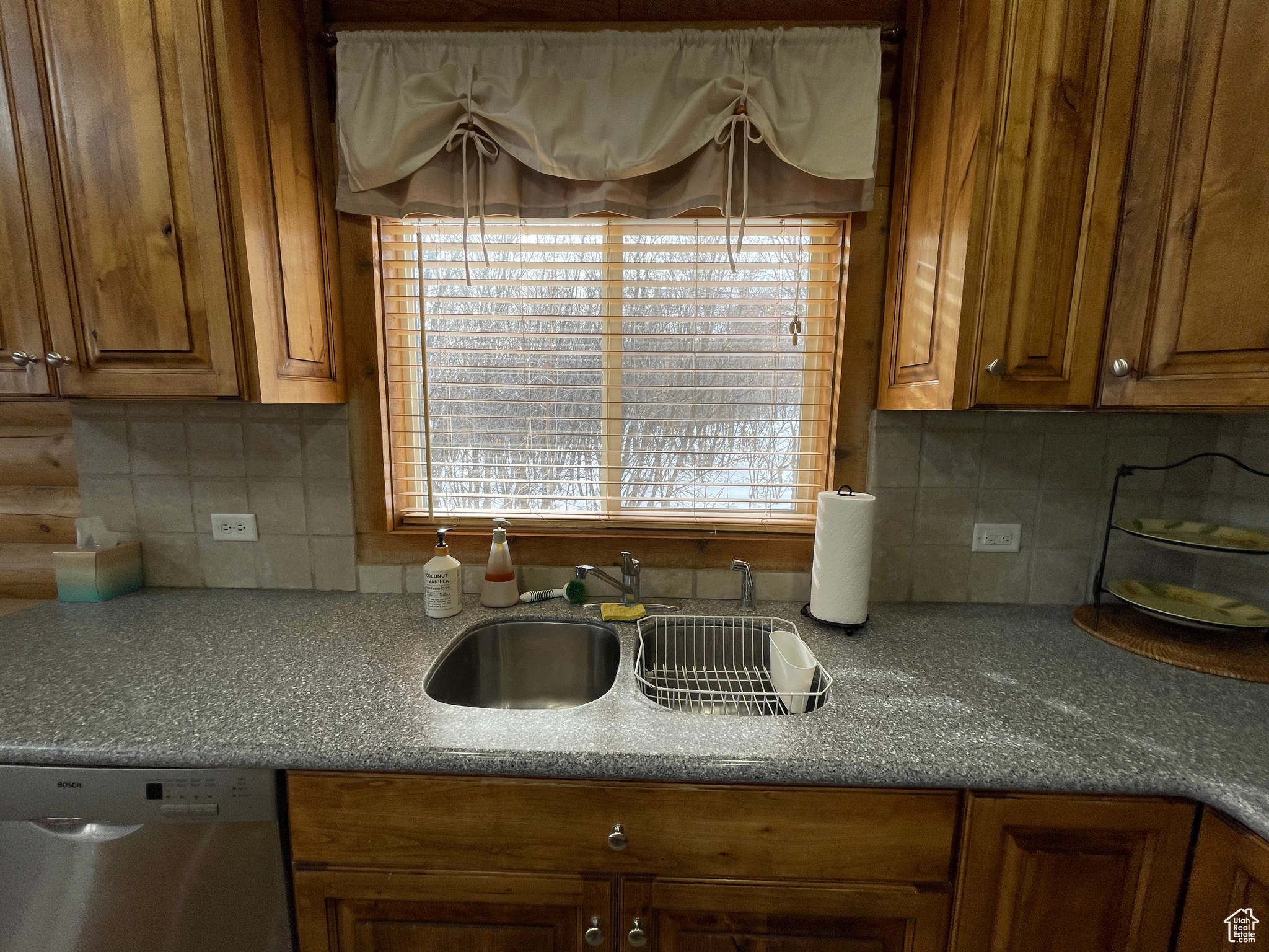 Kitchen featuring tasteful backsplash, dishwasher, and sink