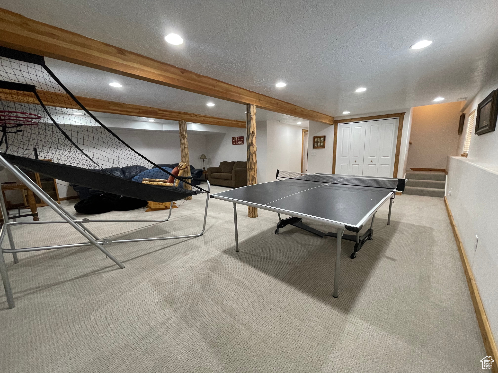 Game room featuring light colored carpet, a textured ceiling, and beam ceiling