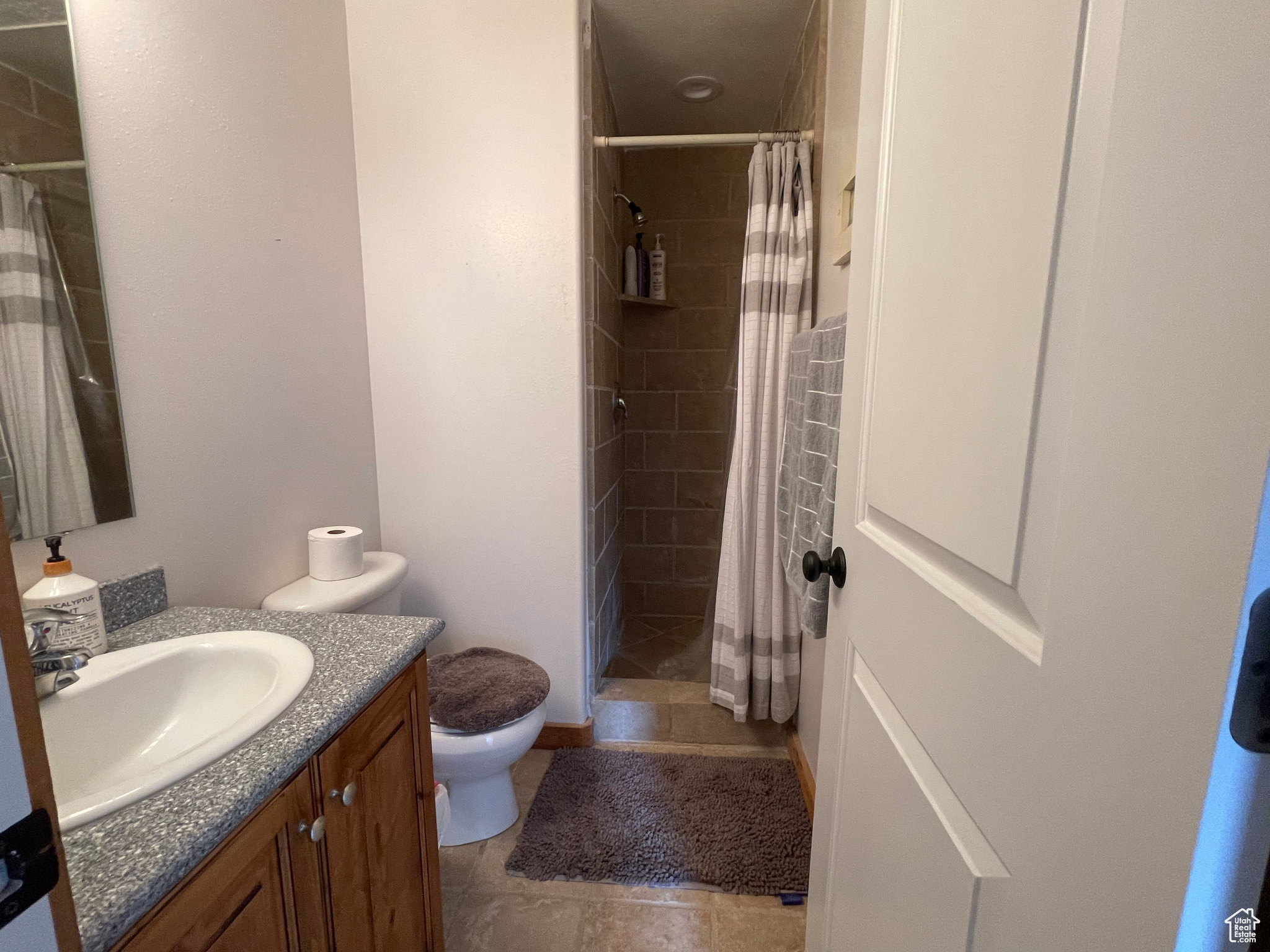 Bathroom featuring tile floors, toilet, a shower with curtain, and vanity