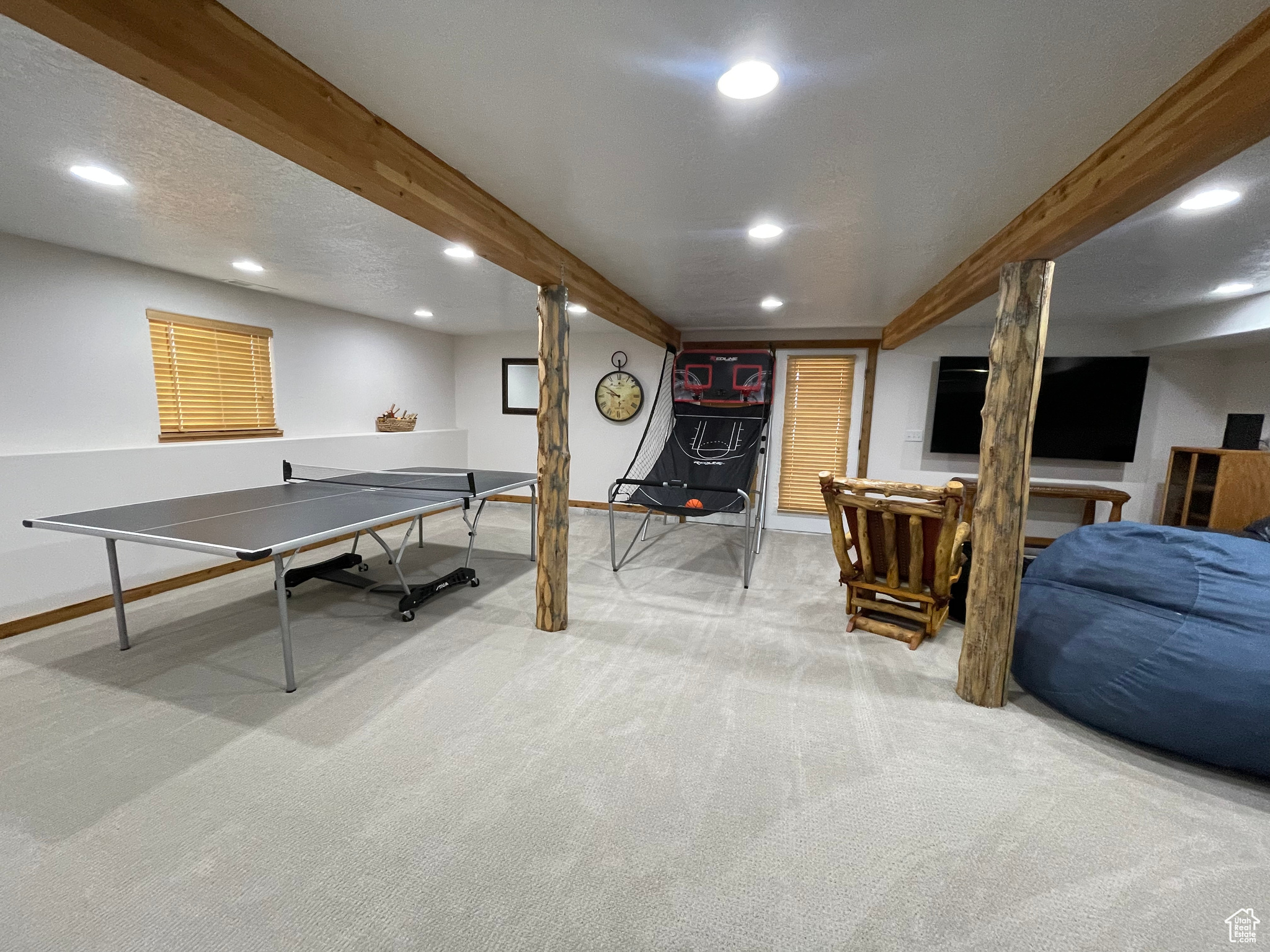 Recreation room featuring a textured ceiling, beamed ceiling, and light colored carpet
