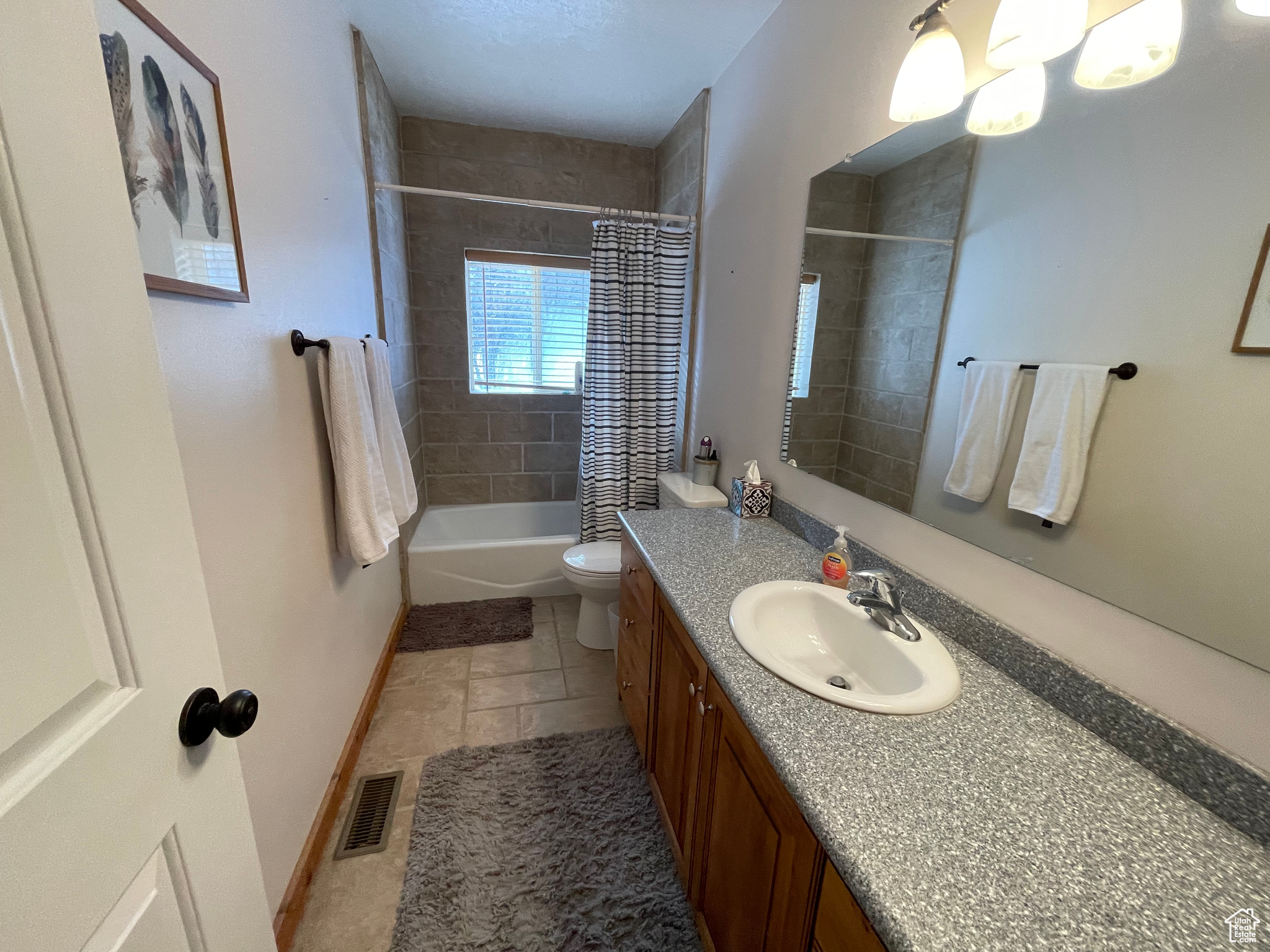 Full bathroom with vanity, toilet, tile flooring, and shower / bathtub combination with curtain