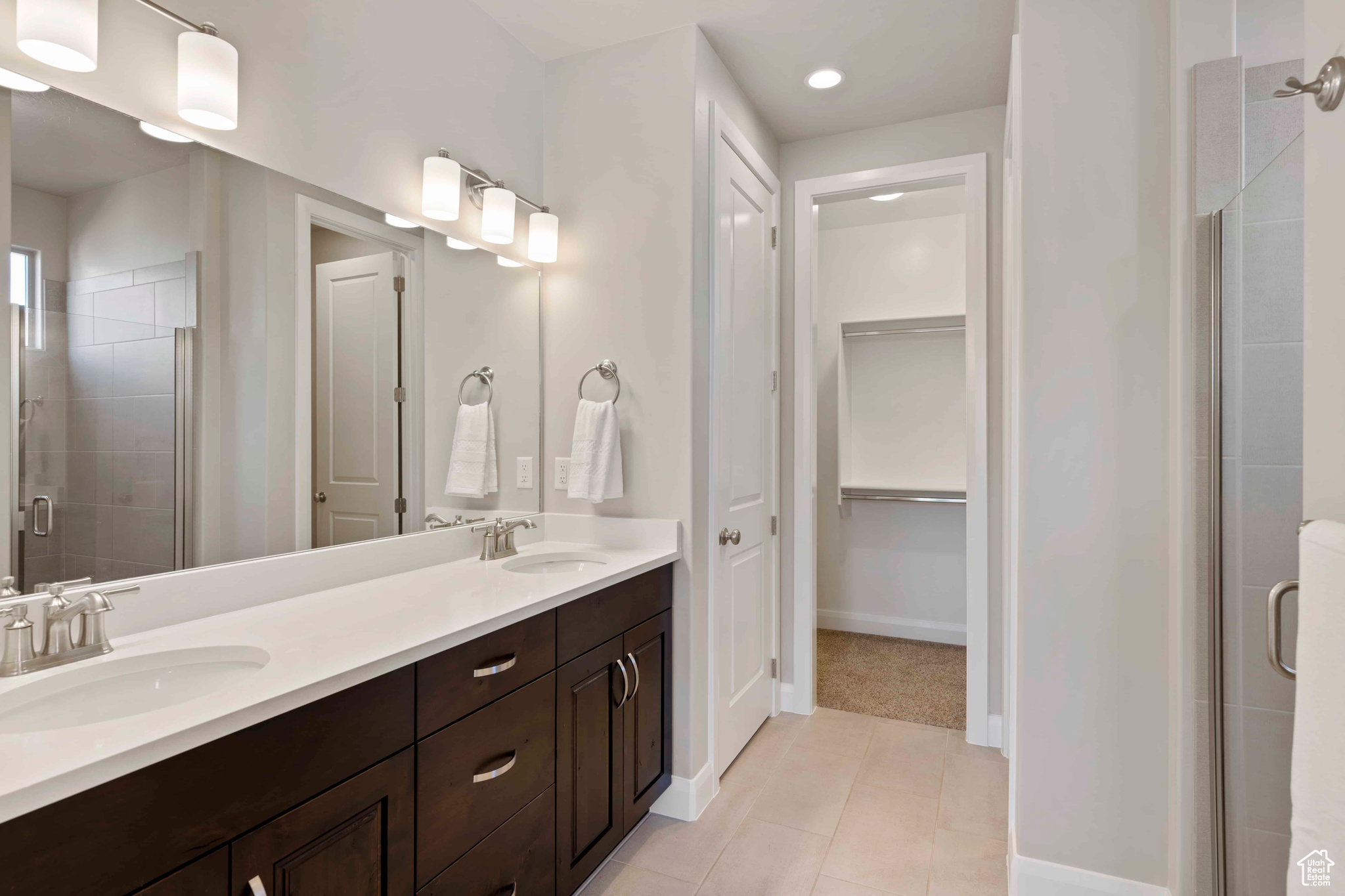 Bathroom with tile floors, a shower with shower door, and double sink vanity