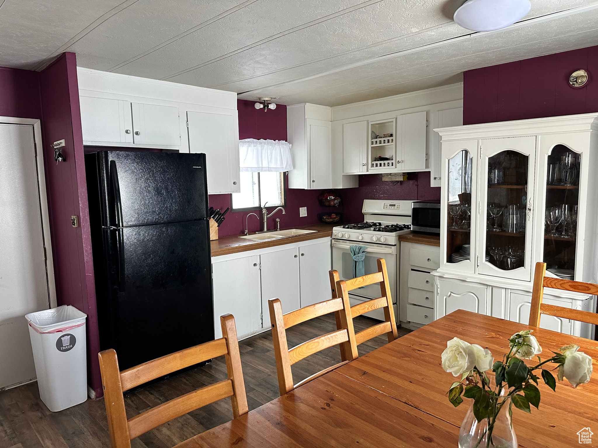 Kitchen with sink, white gas range, black refrigerator, and white cabinets