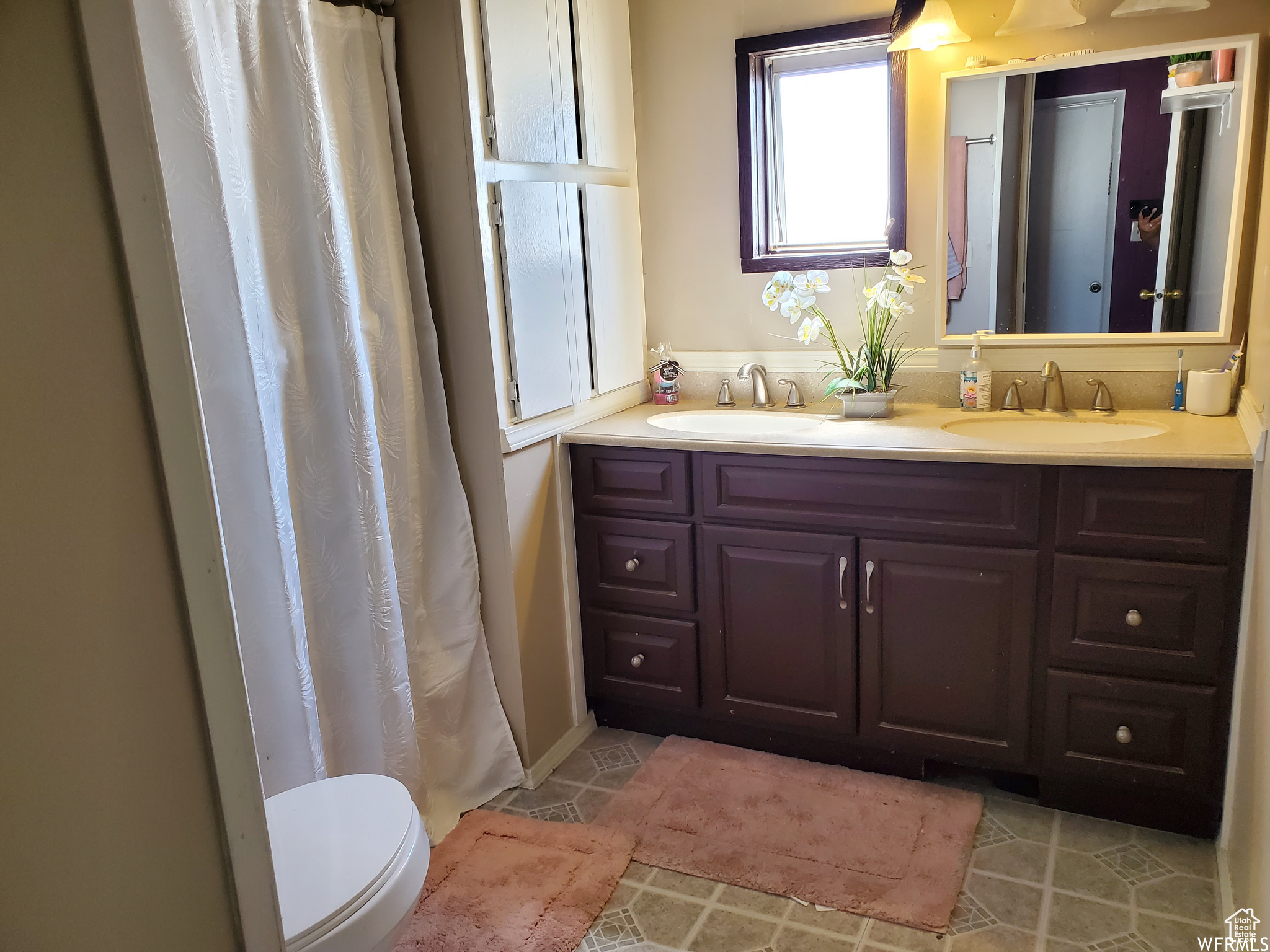 Bathroom with tile floors, toilet, and dual vanity