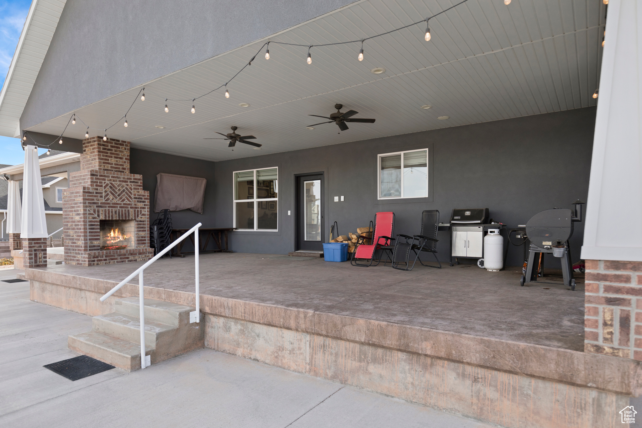 View of terrace featuring an outdoor brick fireplace and ceiling fan