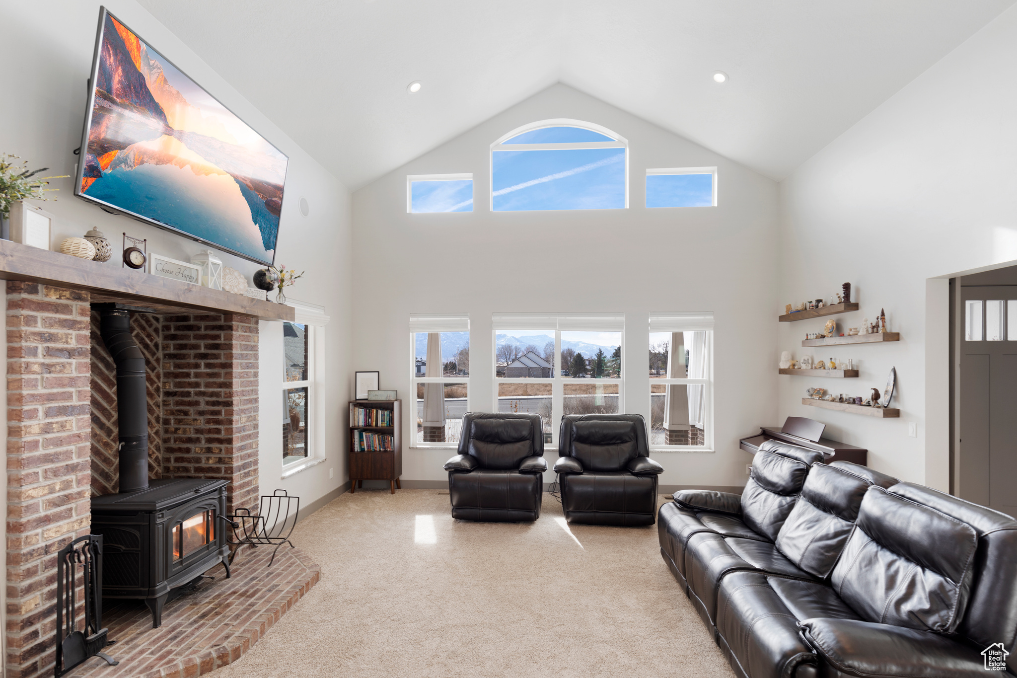 Living room featuring light carpet, a wood stove, and high vaulted ceiling