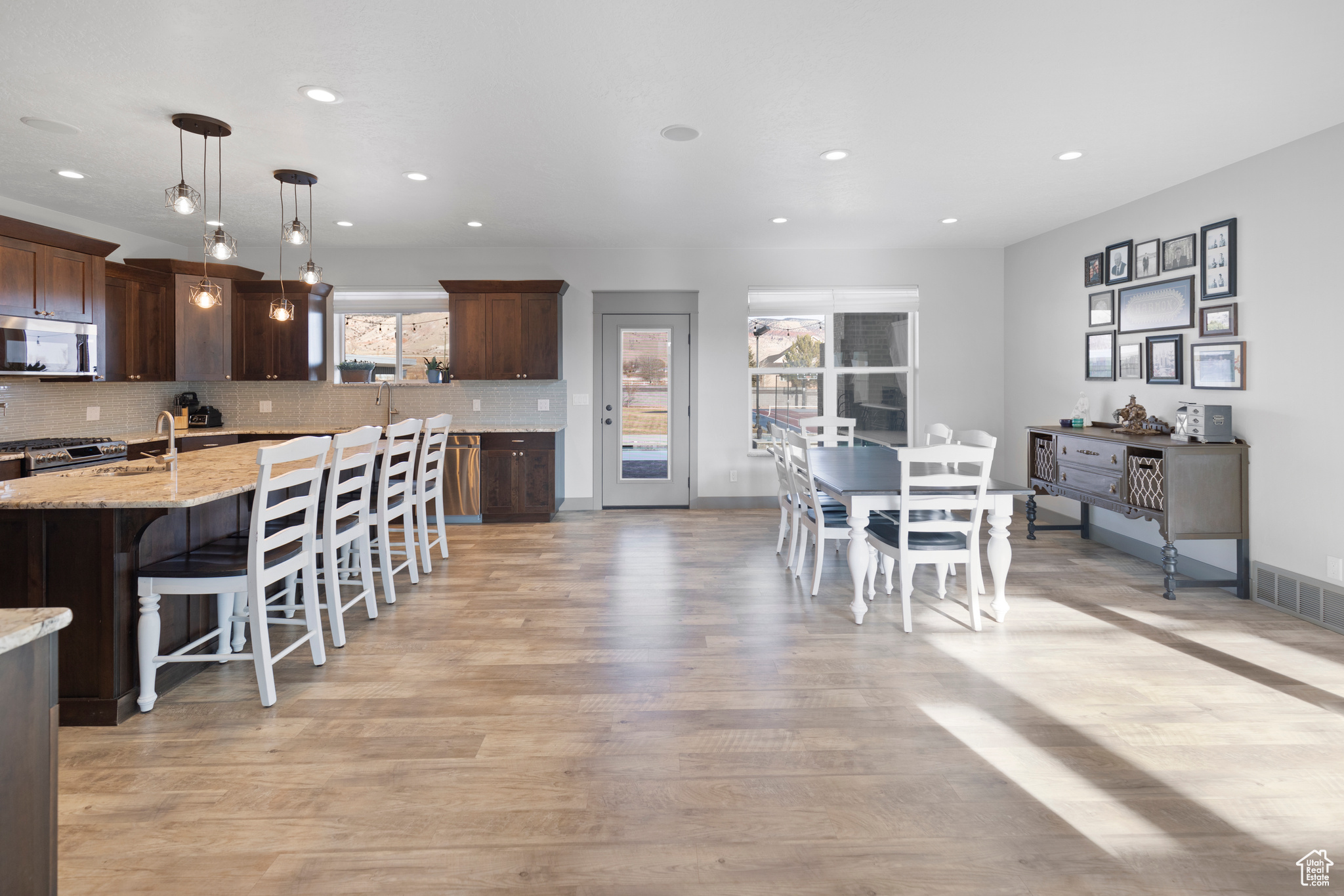 Kitchen featuring tasteful backsplash, stainless steel appliances, light wood-type flooring, and pendant lighting