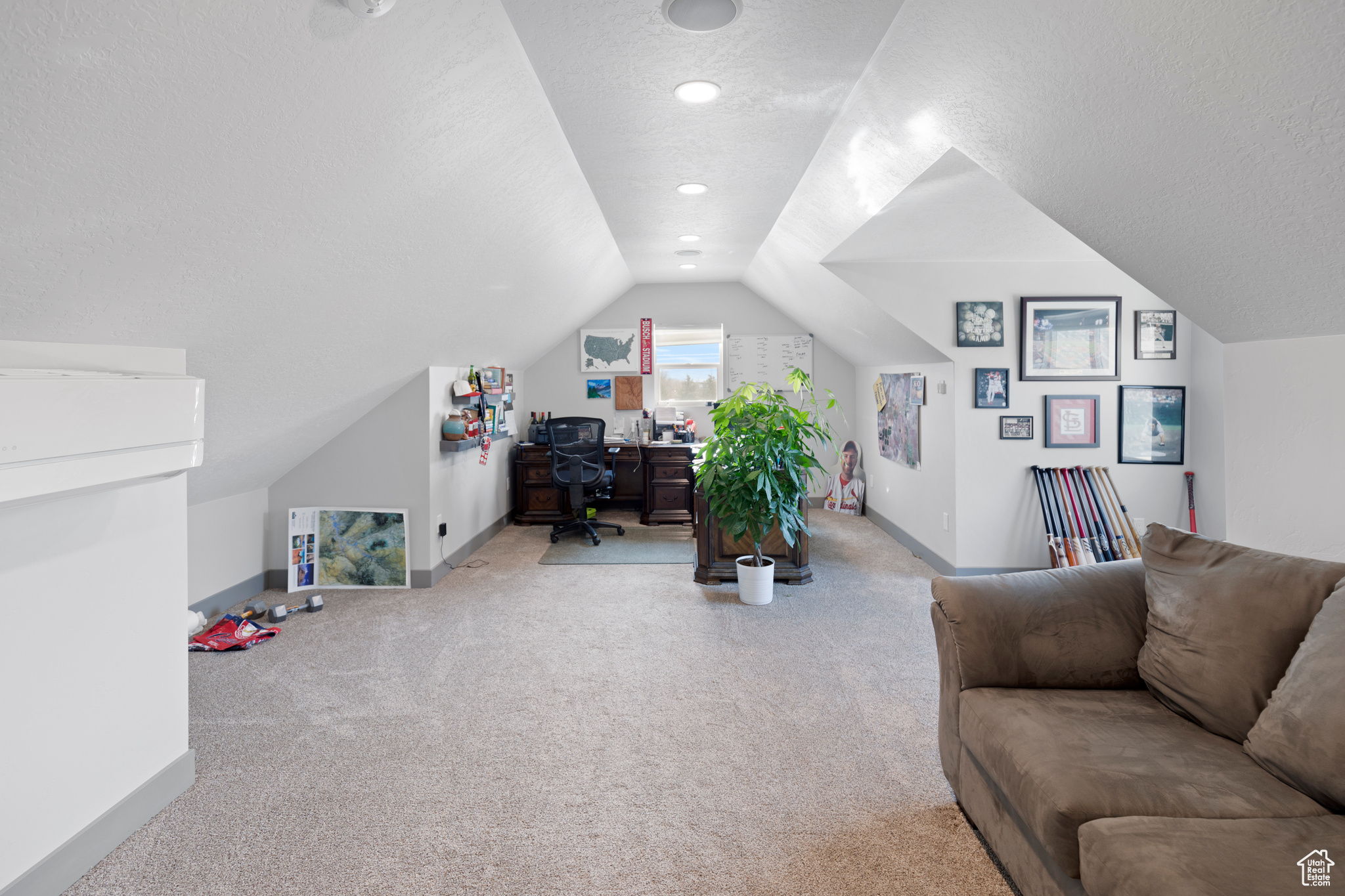 Carpeted office/den featuring a textured ceiling and lofted ceiling