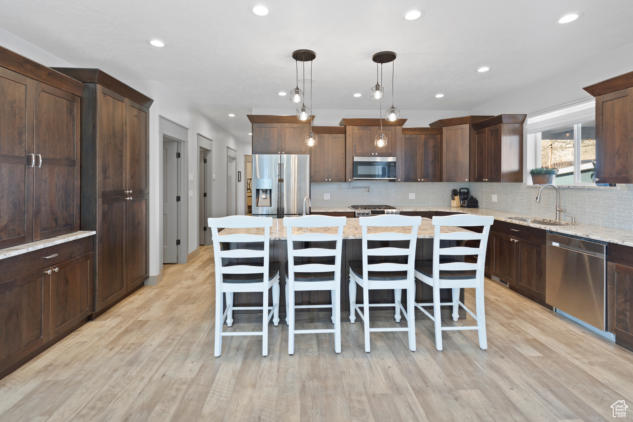 Kitchen with sink, a kitchen island, appliances with stainless steel finishes, and light wood-type flooring