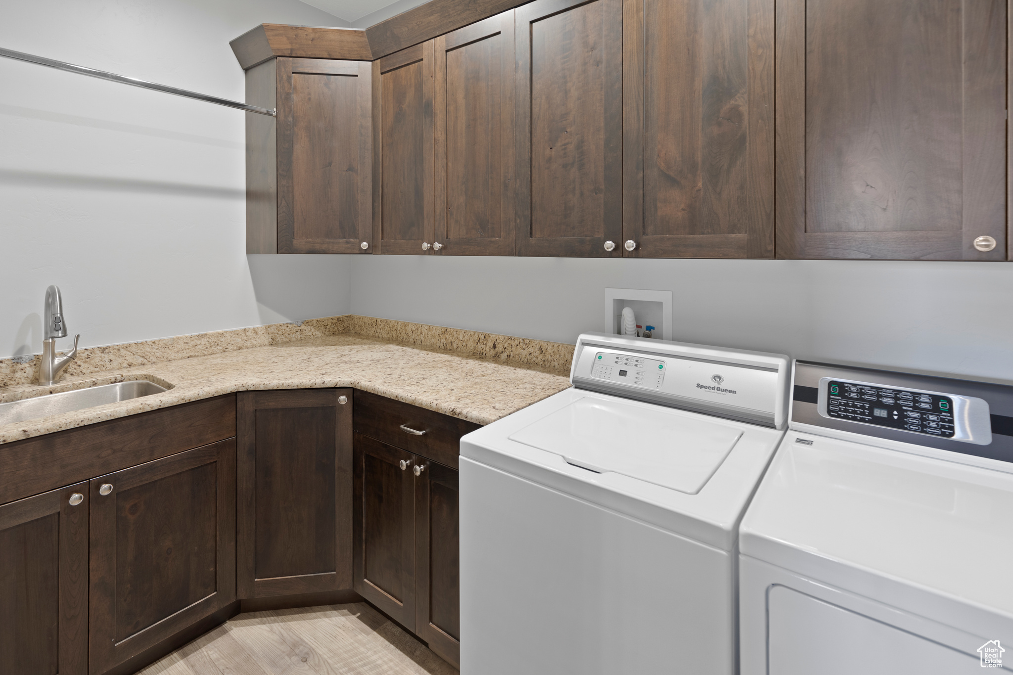 Laundry room featuring cabinets, washing machine and dryer, washer hookup, light wood-type flooring, and sink