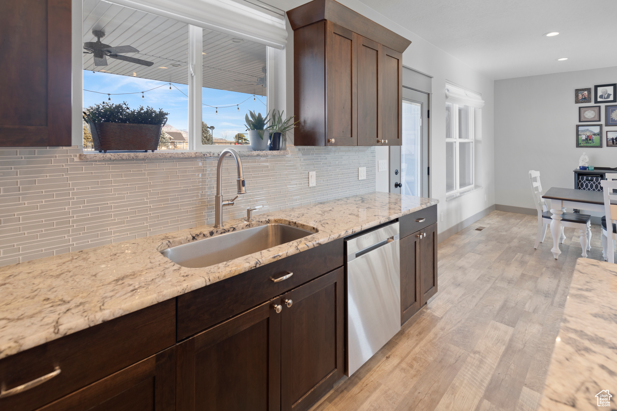 Kitchen with ceiling fan, tasteful backsplash, light hardwood / wood-style flooring, dishwasher, and sink