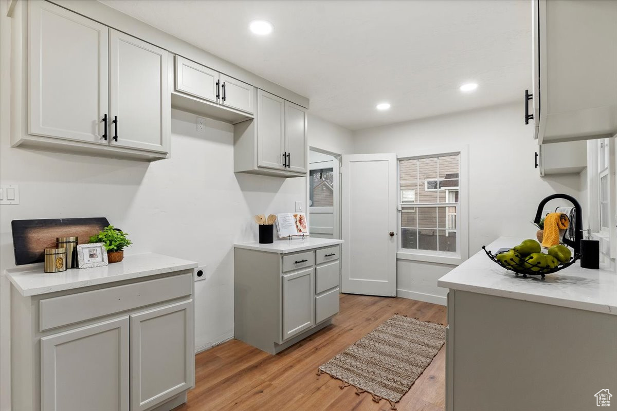 Kitchen with light hardwood / wood-style flooring, light stone counters, and gray cabinets