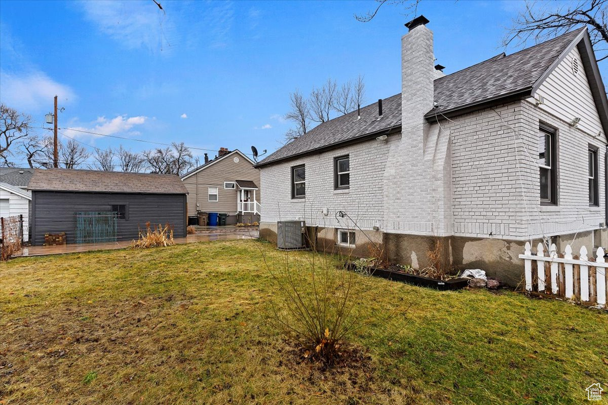 Back of house with a lawn and central AC unit