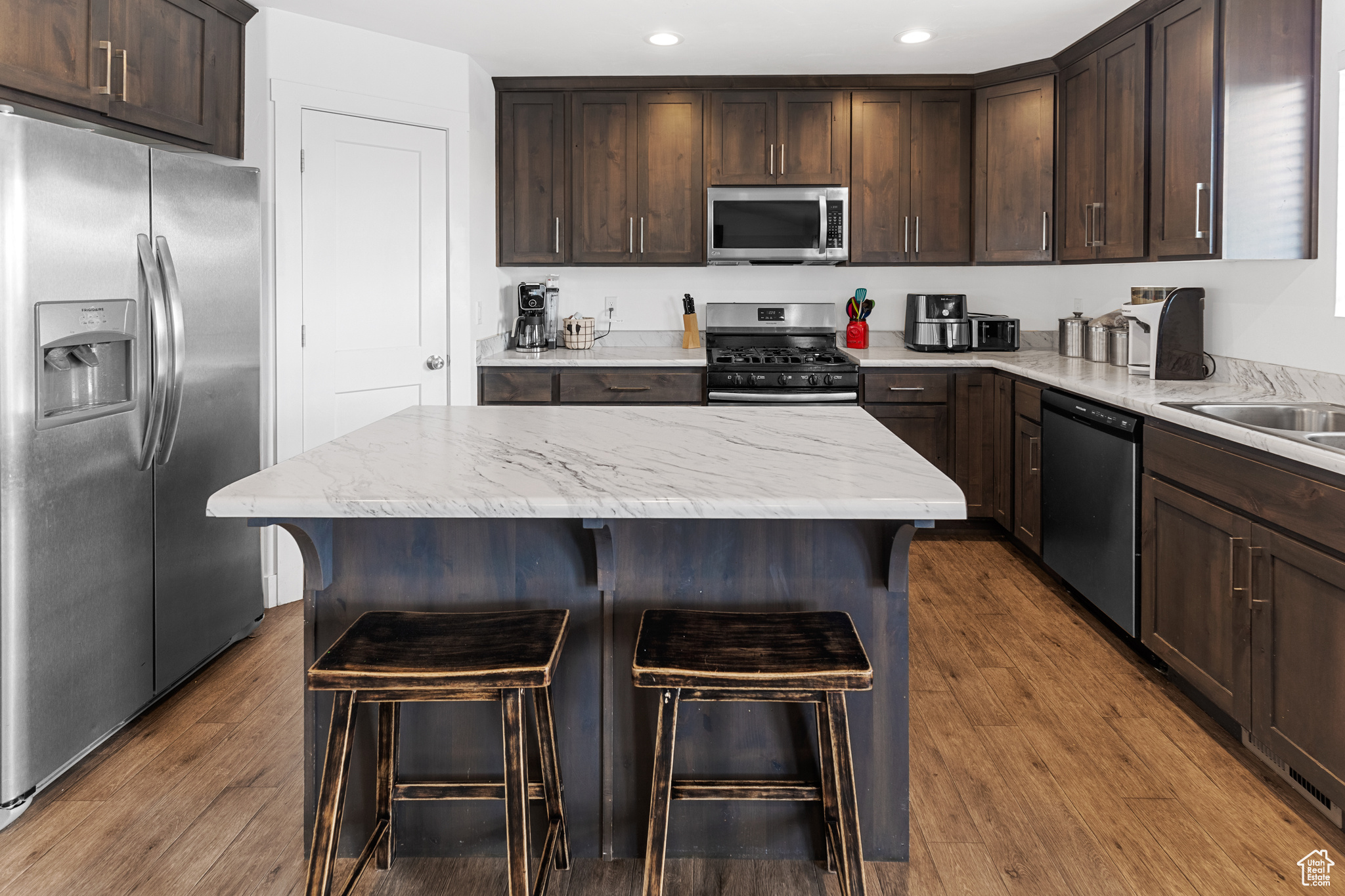 Kitchen featuring a kitchen island, a kitchen breakfast bar, stainless steel appliances, and hardwood / wood-style flooring
