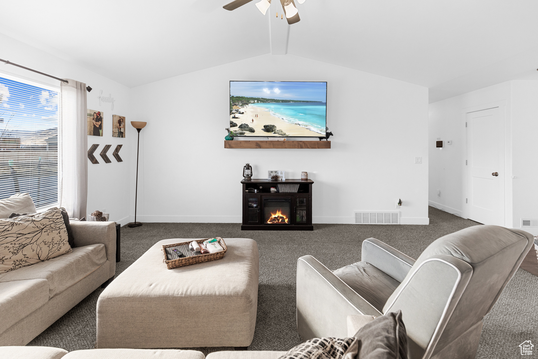 Living room featuring vaulted ceiling, dark carpet, and ceiling fan