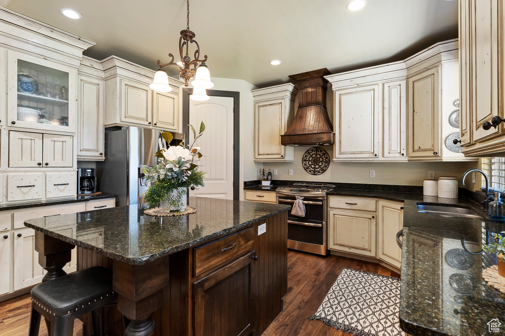 Kitchen featuring custom exhaust hood, a chandelier, appliances with stainless steel finishes, a center island, and dark hardwood / wood-style floors