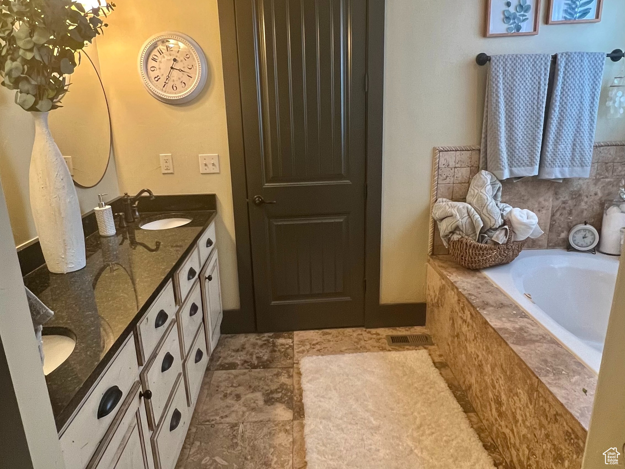 Bathroom featuring tiled bath, tile floors, large vanity, and double sink