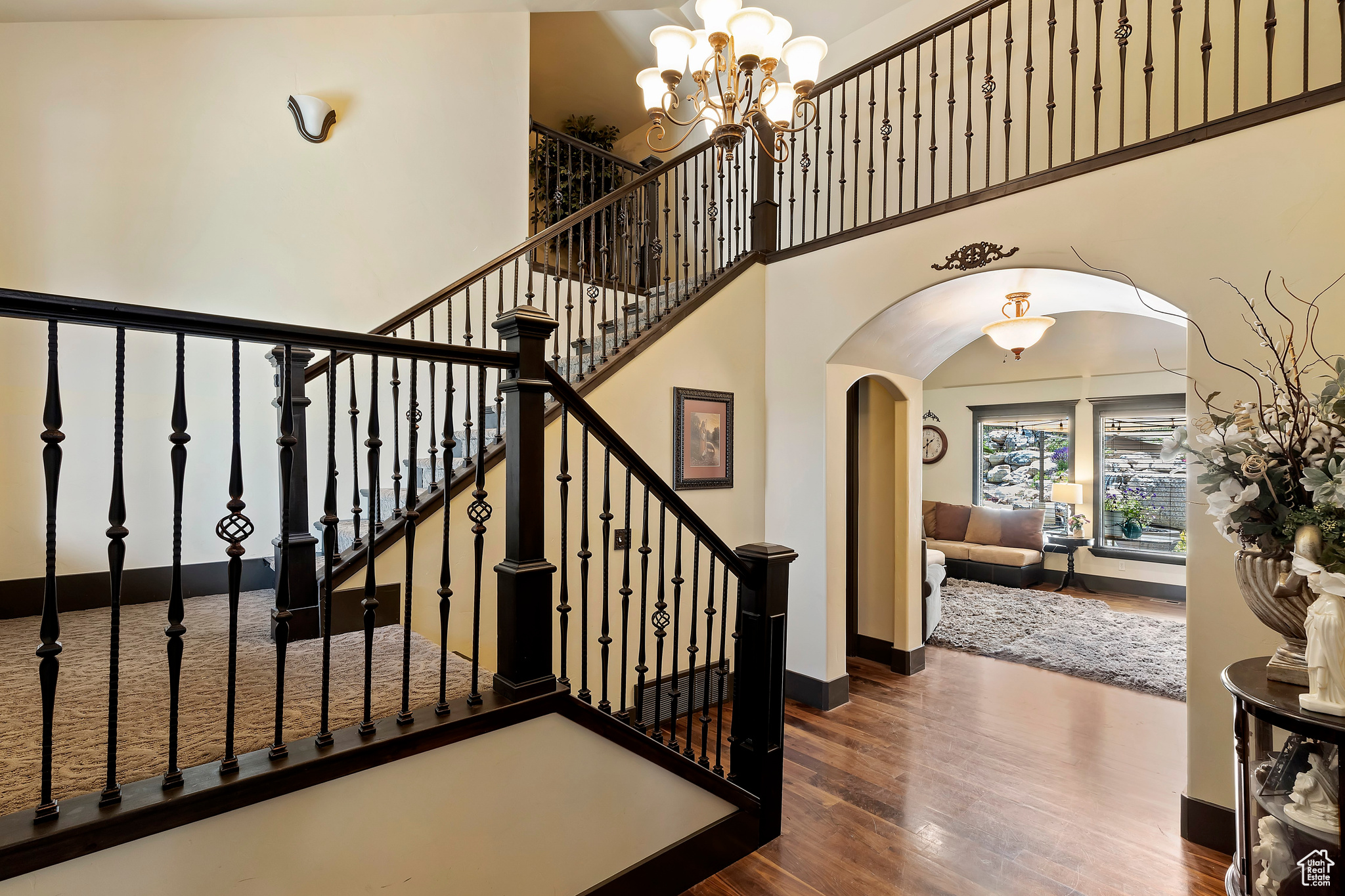 Stairway with an inviting chandelier, dark hardwood / wood-style flooring, and high vaulted ceiling