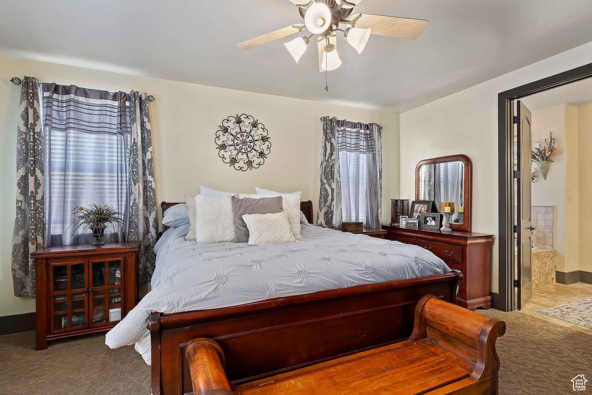 Bedroom featuring dark colored carpet, ensuite bath, and ceiling fan